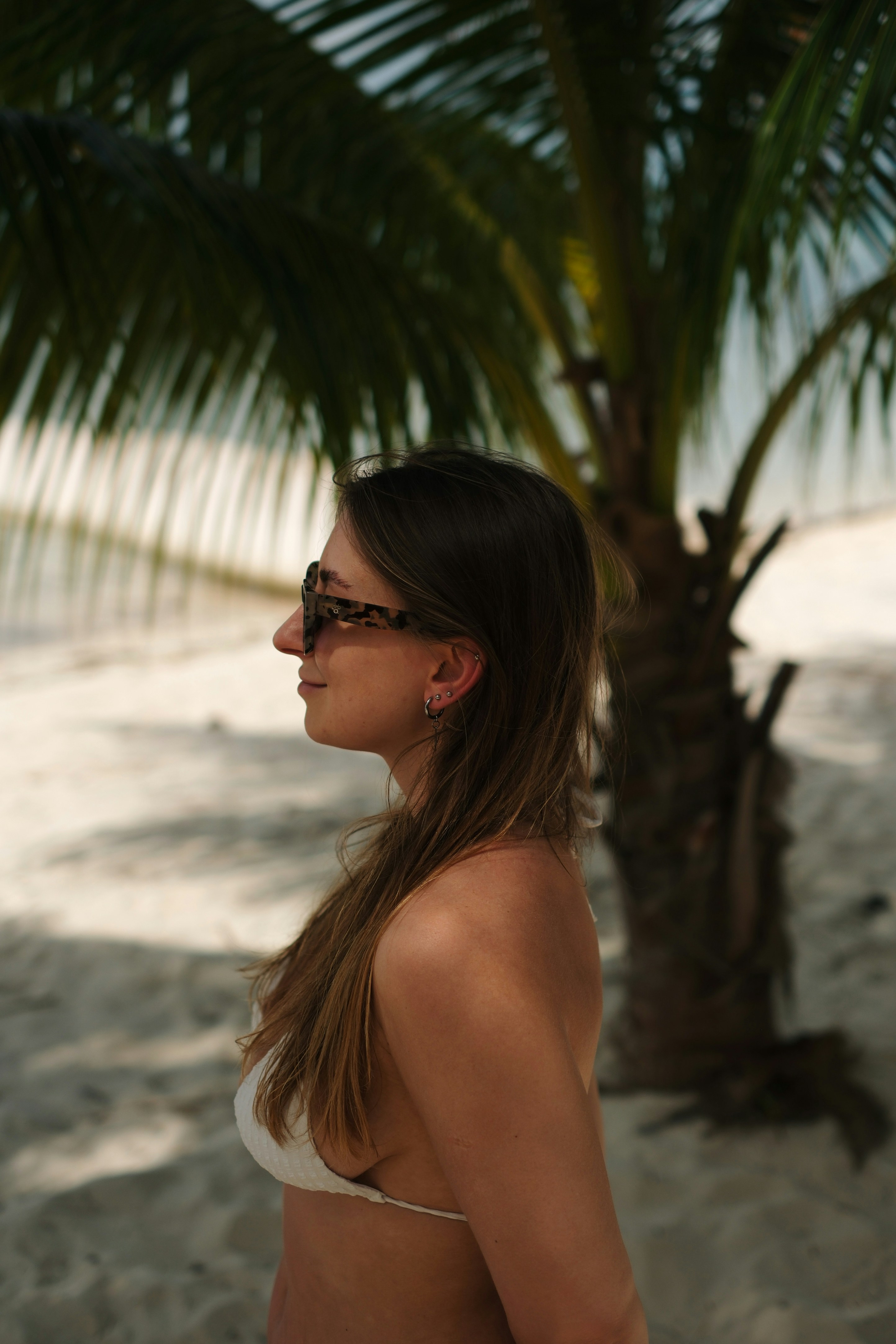 Woman in bikini standing on a sandy beach.