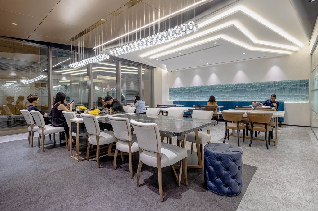مساحة مكتبية حديثة تضم منطقة طعام واسعة وجدارًا زجاجيًا بارزًا يضفي إضاءة طبيعية وانسيابية، مثالية لمكاتب الحاصلين على رخصة تجارة الكترونية دبي.