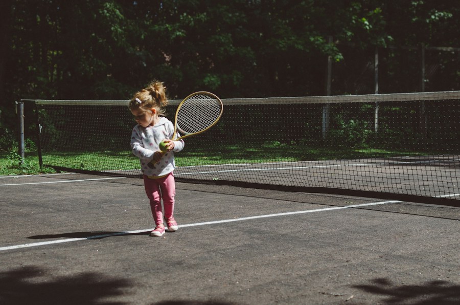 A small girl swinging a tennis racket on a court