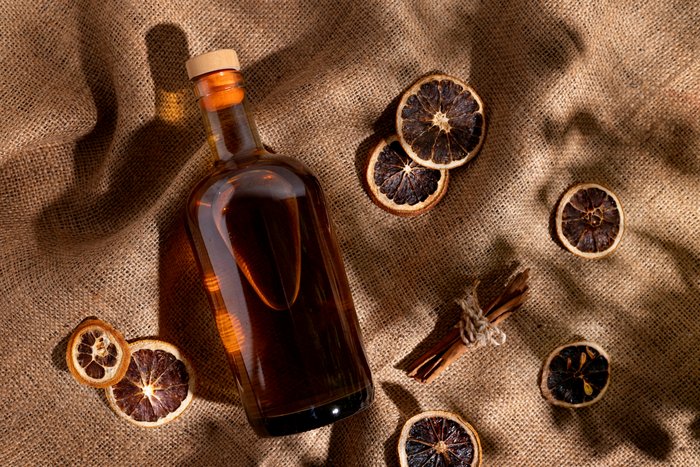 Premium spirits packaging with a cork stopper on a glass bottle, surrounded by dried citrus slices on burlap.