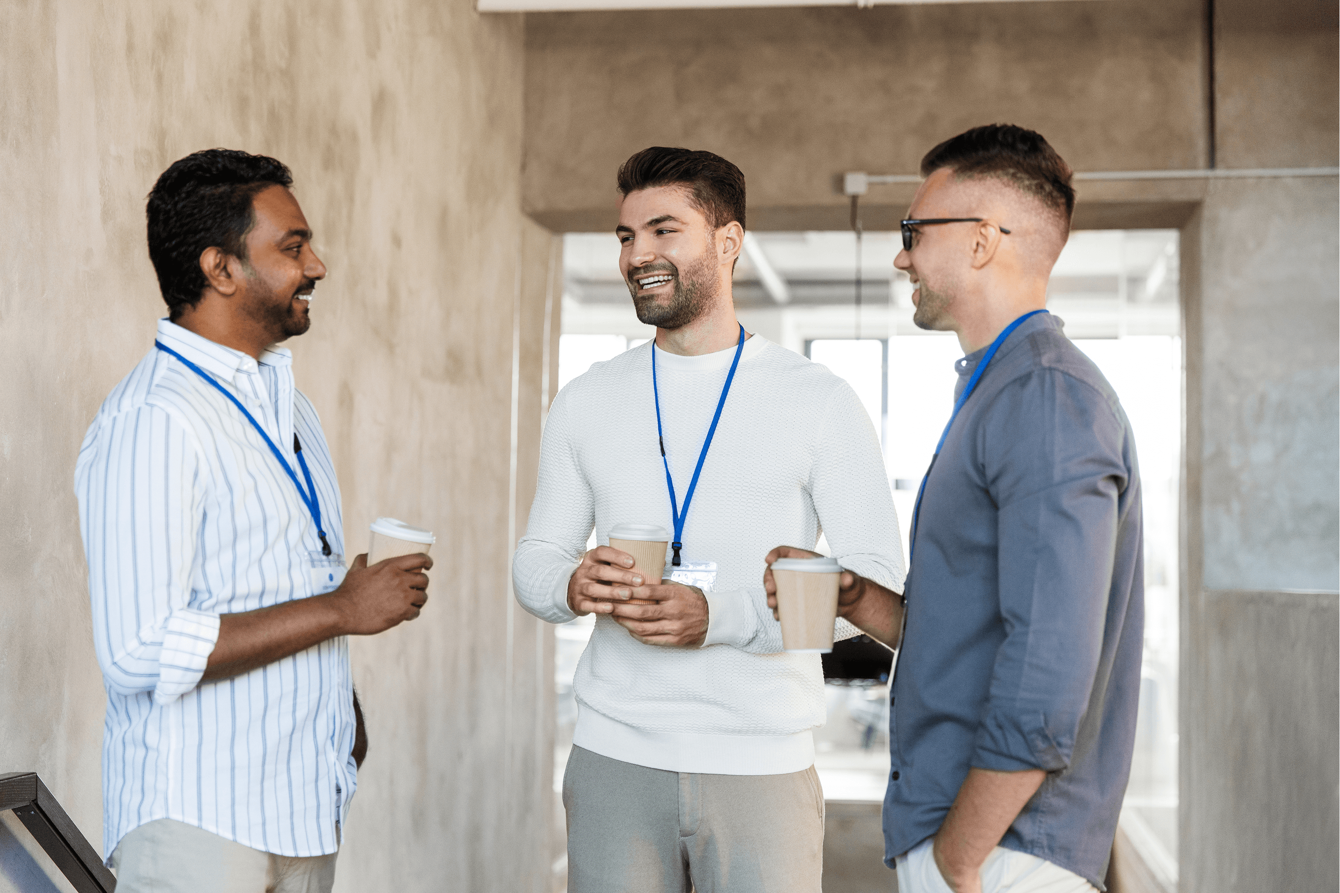 Professional men engaging in workplace collaboration and networking during an office coffee break.