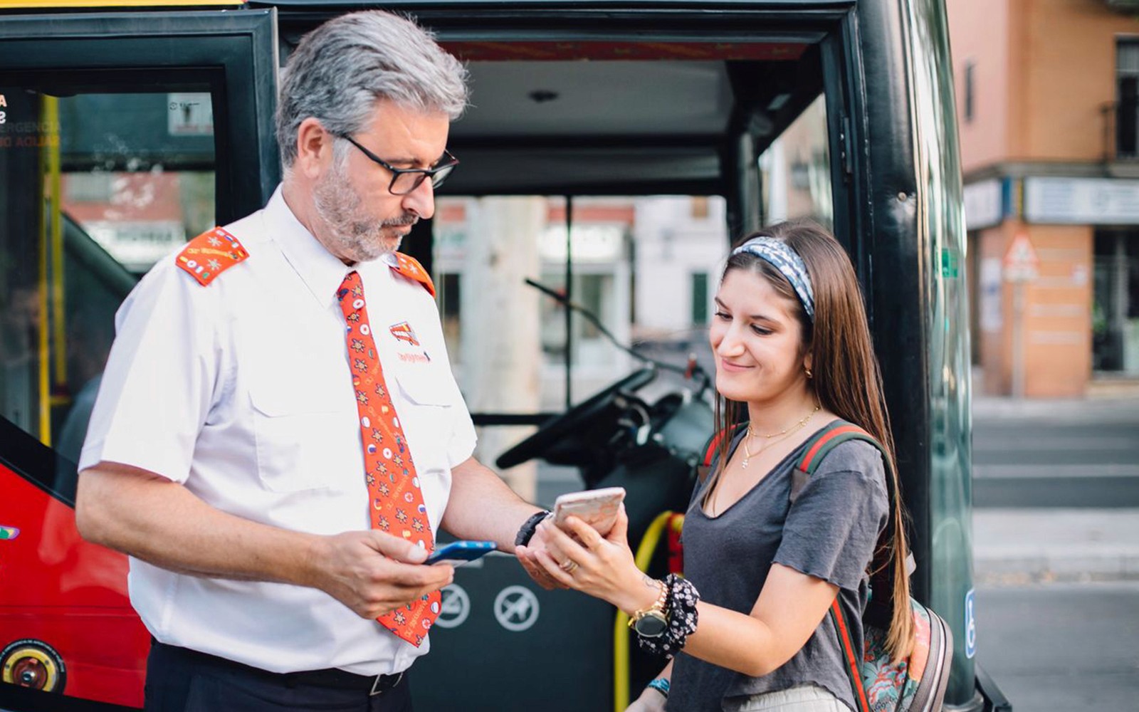 Buszsofőr segít a turistának a jeggyel a Thessaloniki Hop-On-Hop-Off túrán.
