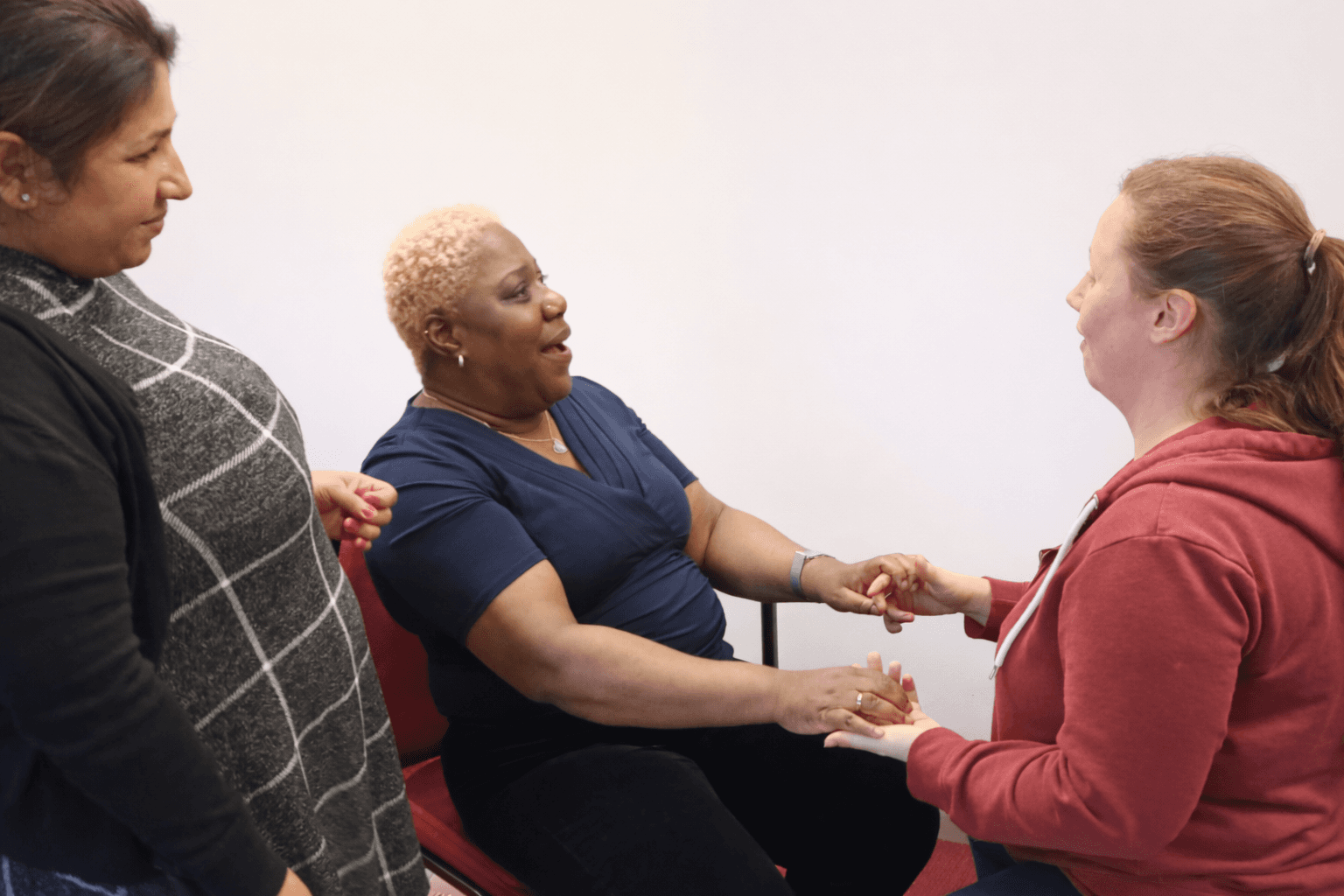 A group of people sitting in a circle in a room, engaging in a group discussion or signing session