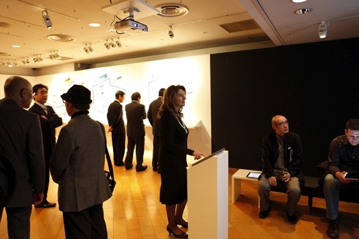 people looking at the wall to an image projection, and other groups are talking and looking at different presentations