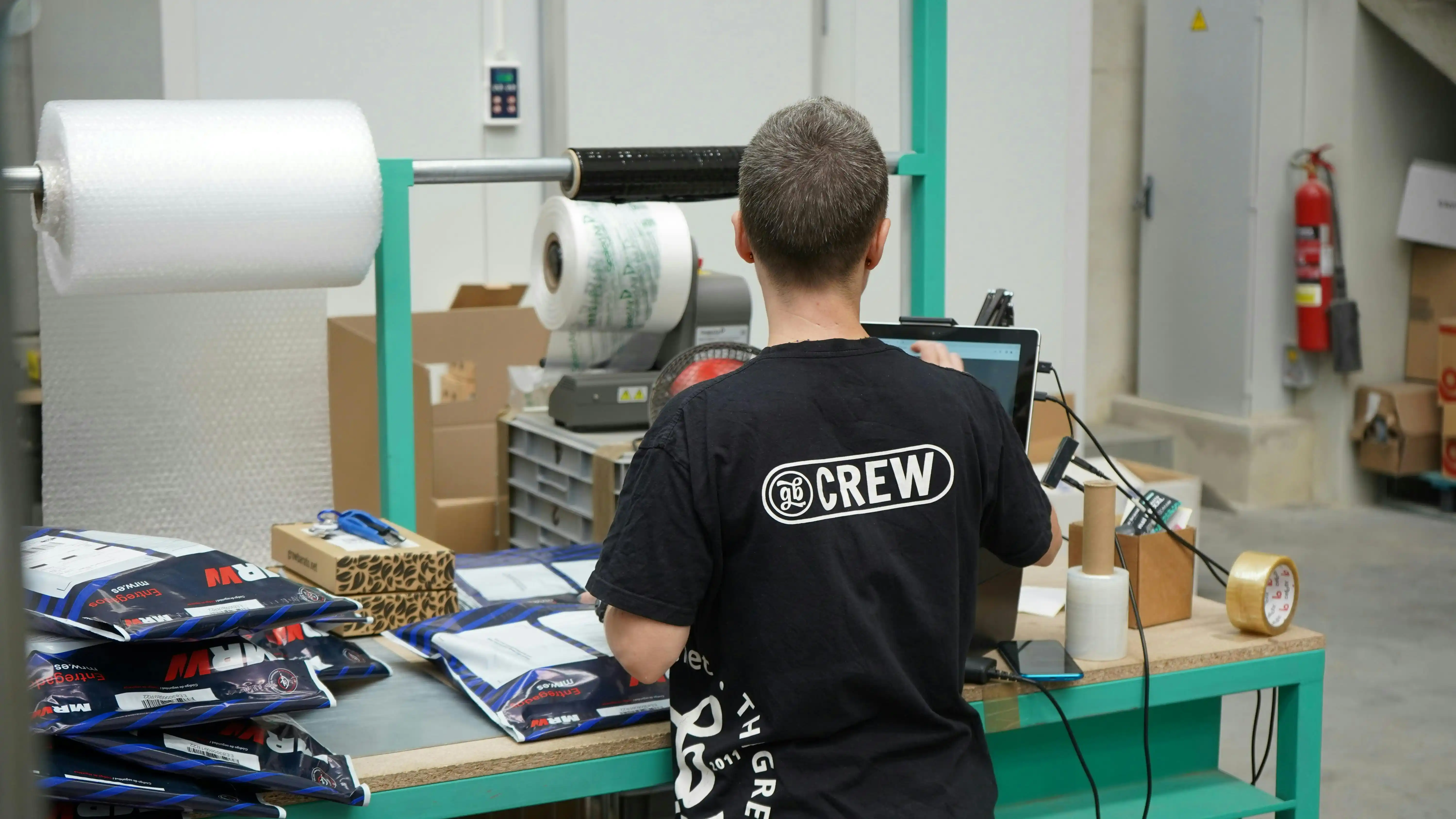 a warehouse worker packs orders at a packing table at a 3PL fulfilment centre