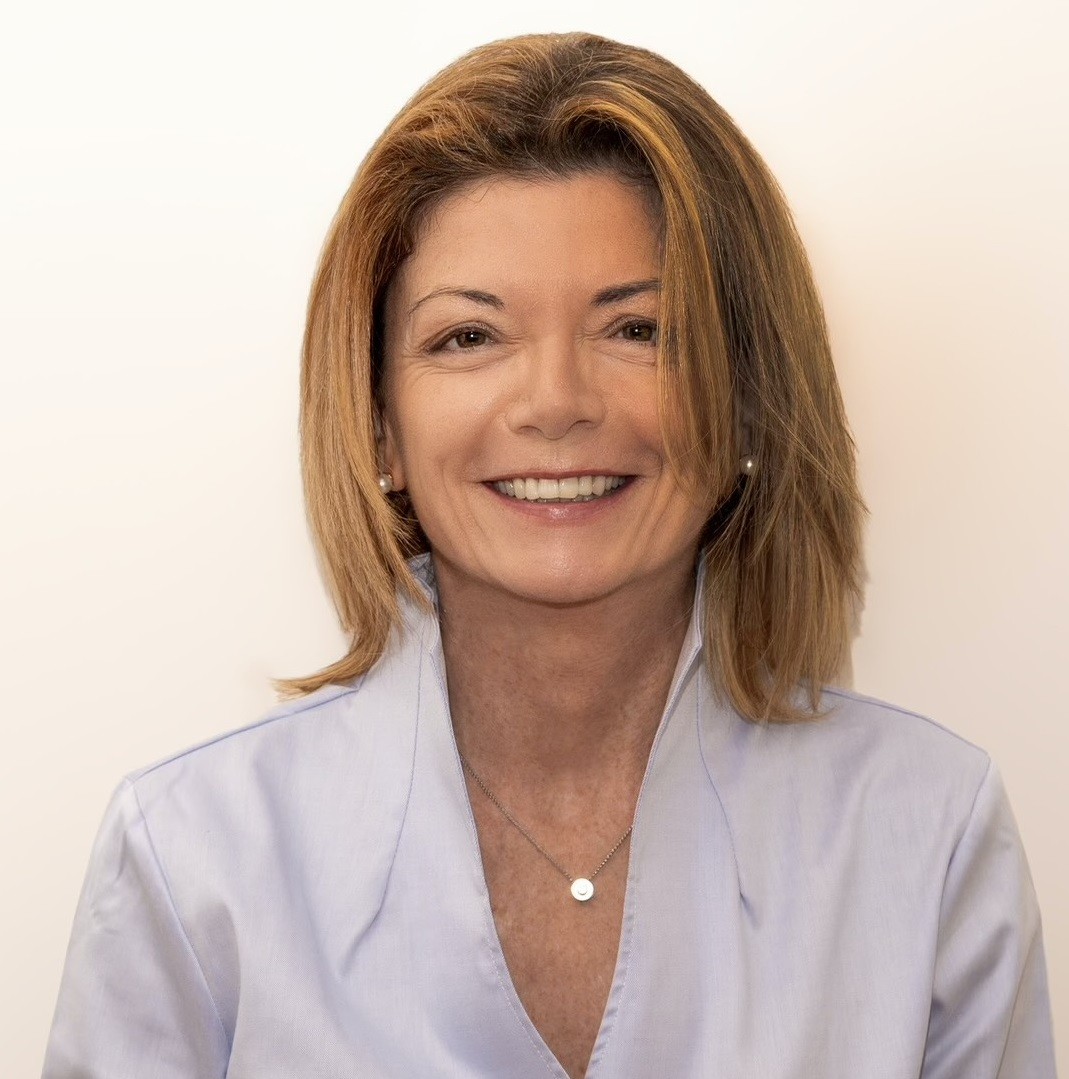A man with glasses and a beard is looking directly at the camera, seated in a cozy, dimly lit café.