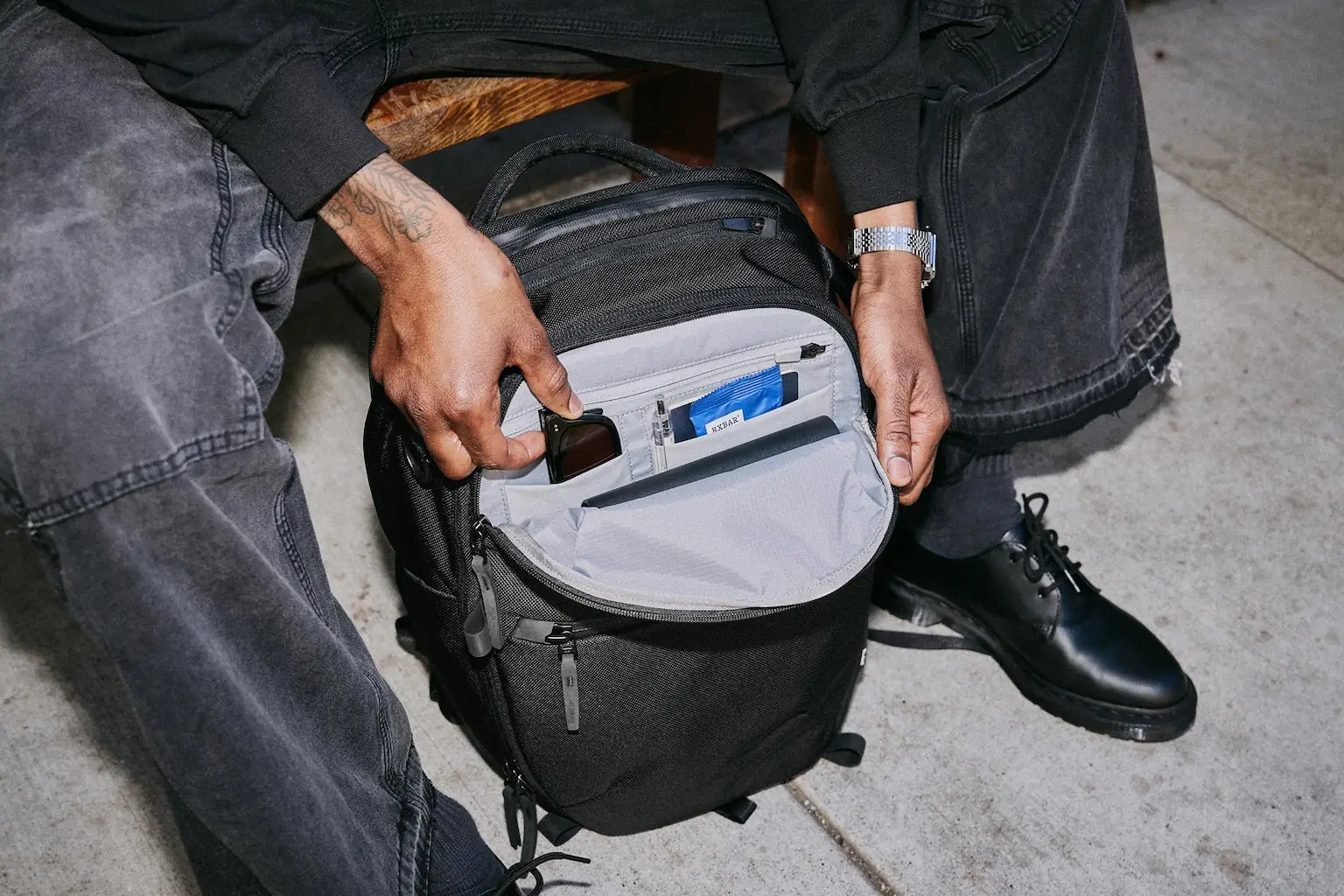 Man opening top compartment of black backpack