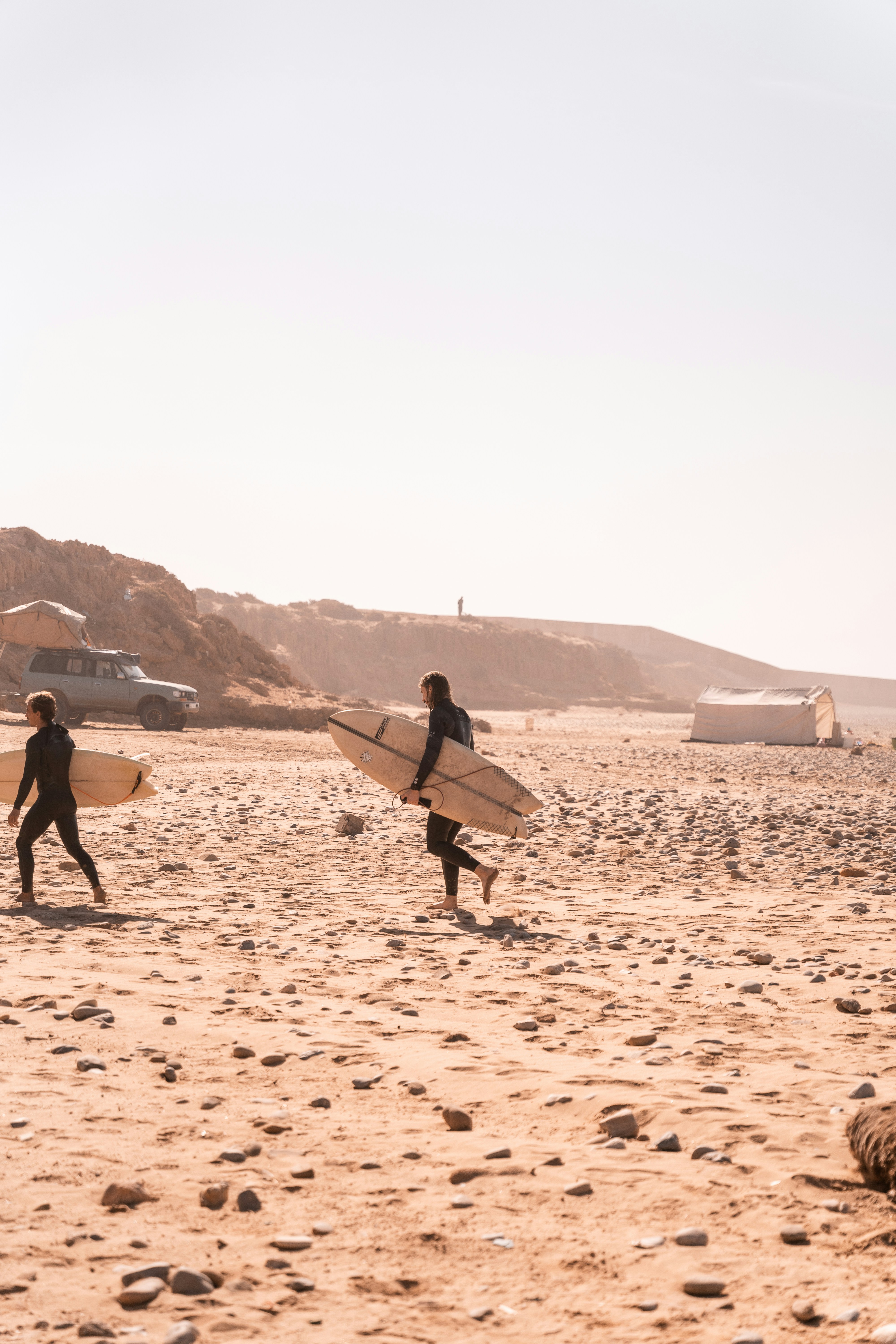 a group of people carrying surfboards on top of a beach
