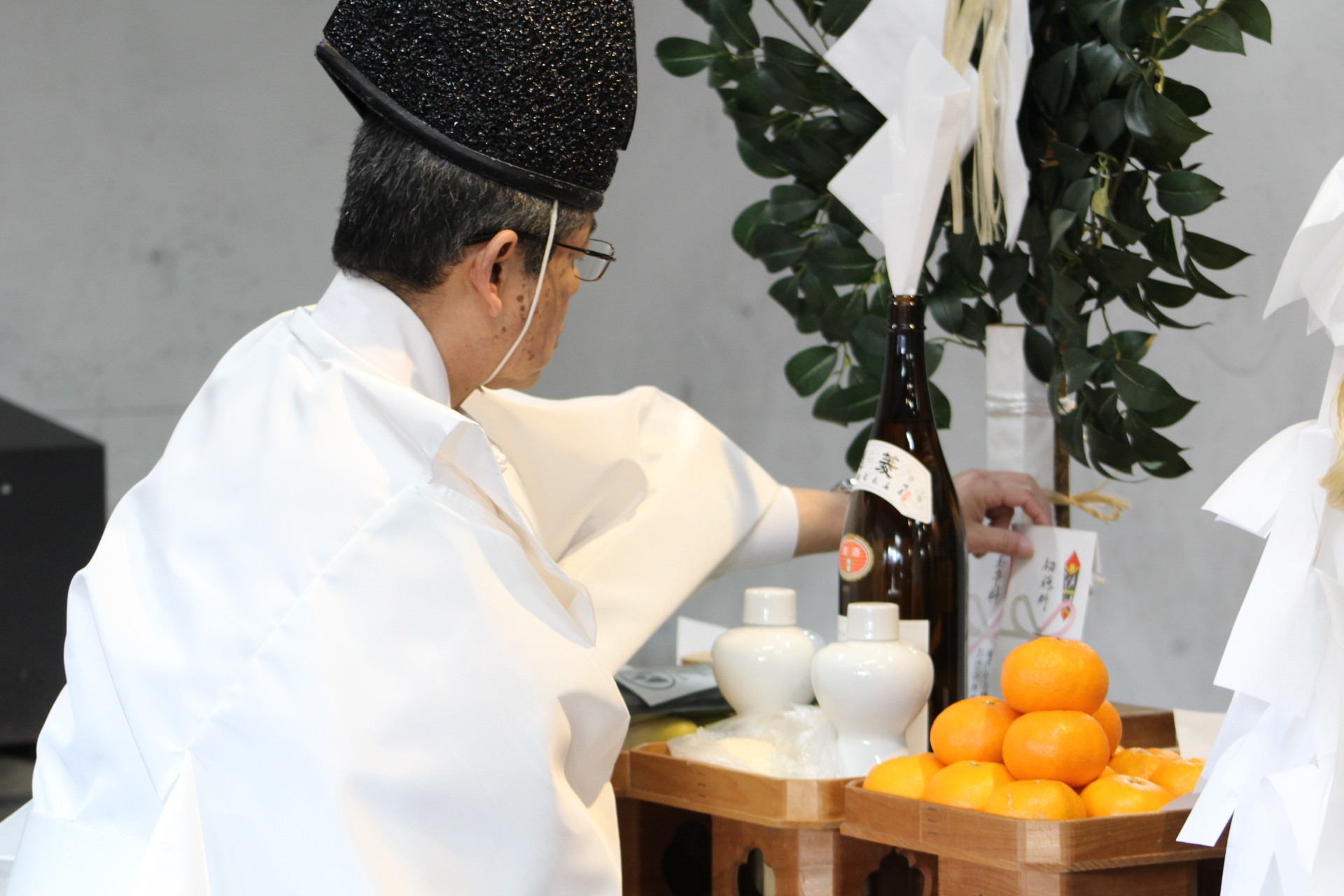 Shinto priest performing a ritual with Japanese sake and orange on the altar