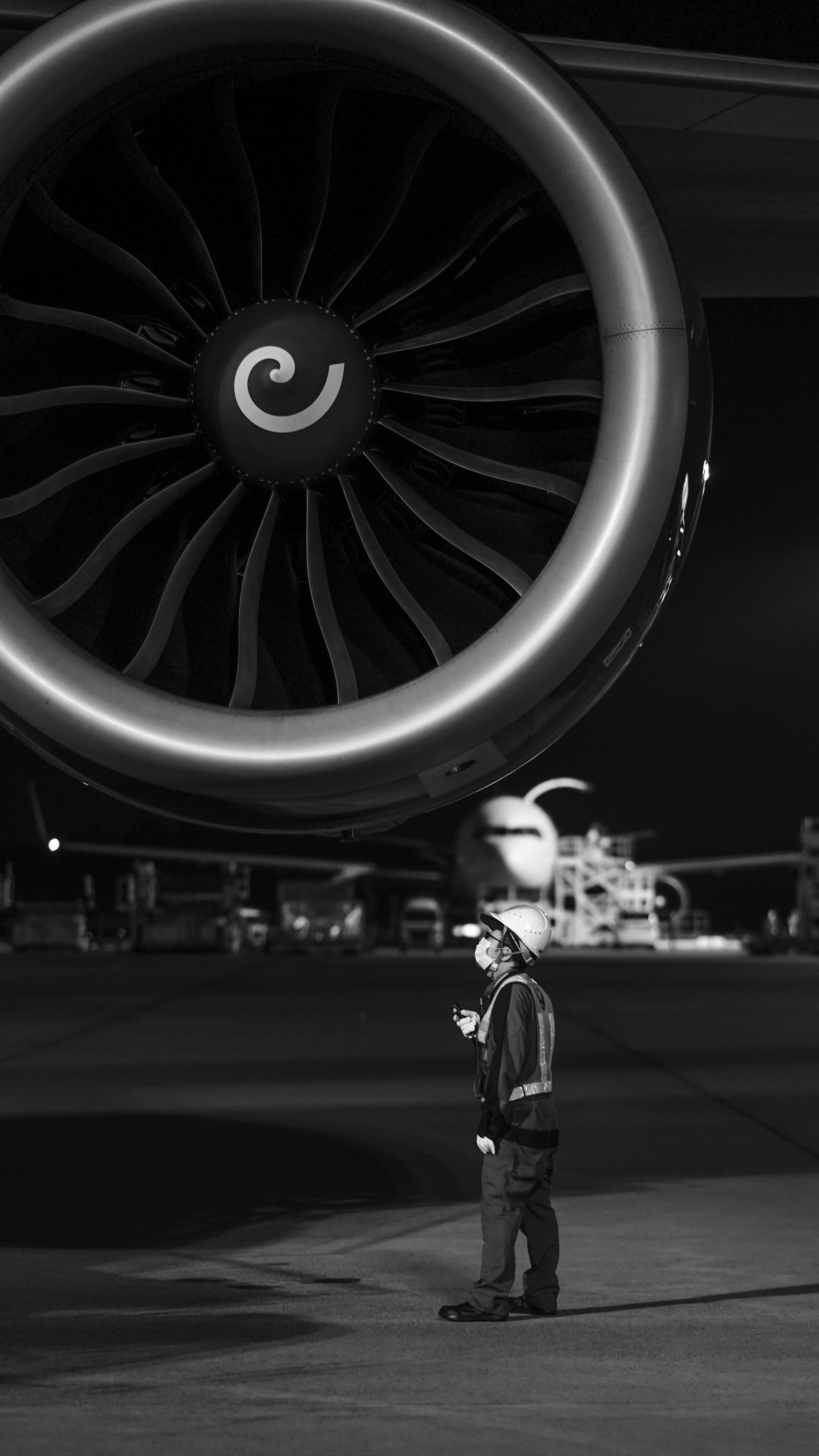 Close-up of jet engine with ground crew technician