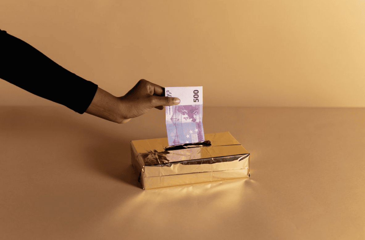 Personne déposant un billet de 500 euros dans une tirelire, symbole d'un premier investissement accessible en non coté