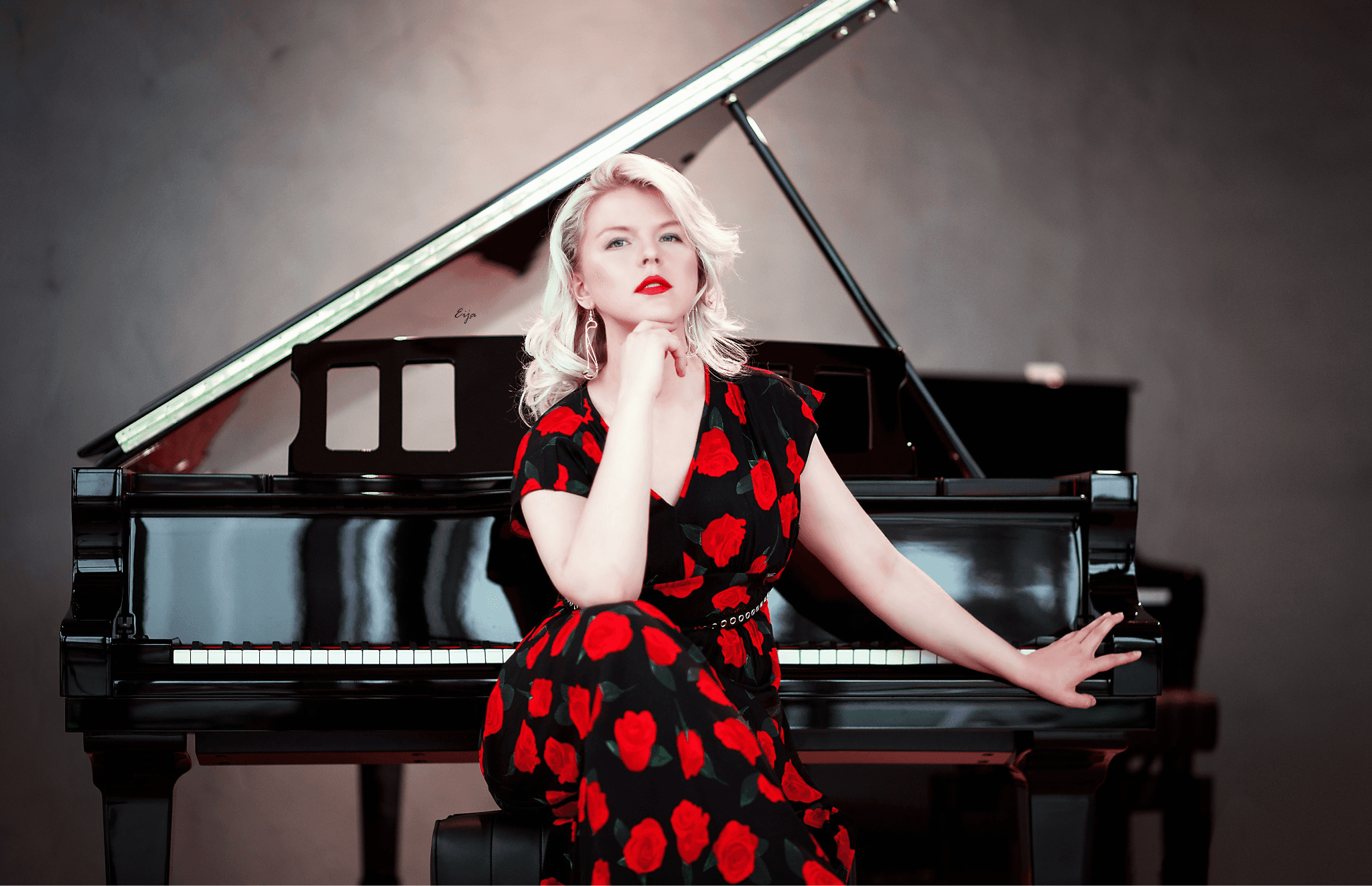 Ellen Fischerová in a black dress with red roses posed in front of a black grand piano.