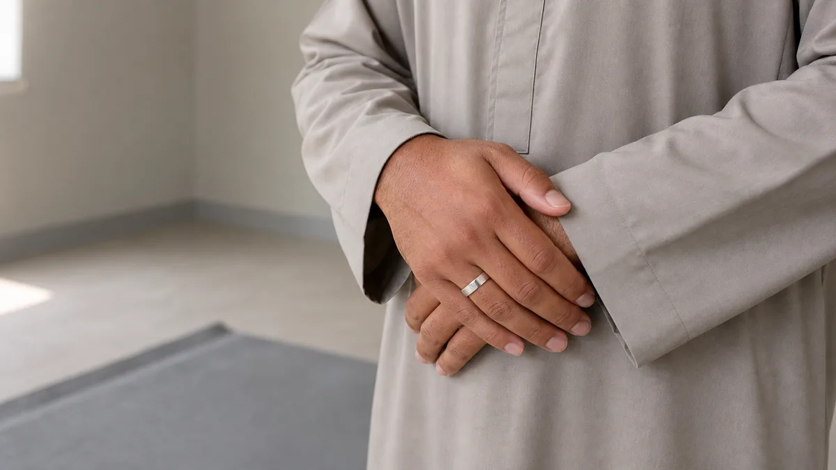 Hands folded in qiyam wearing a plain silver smart tasbih ring during salah