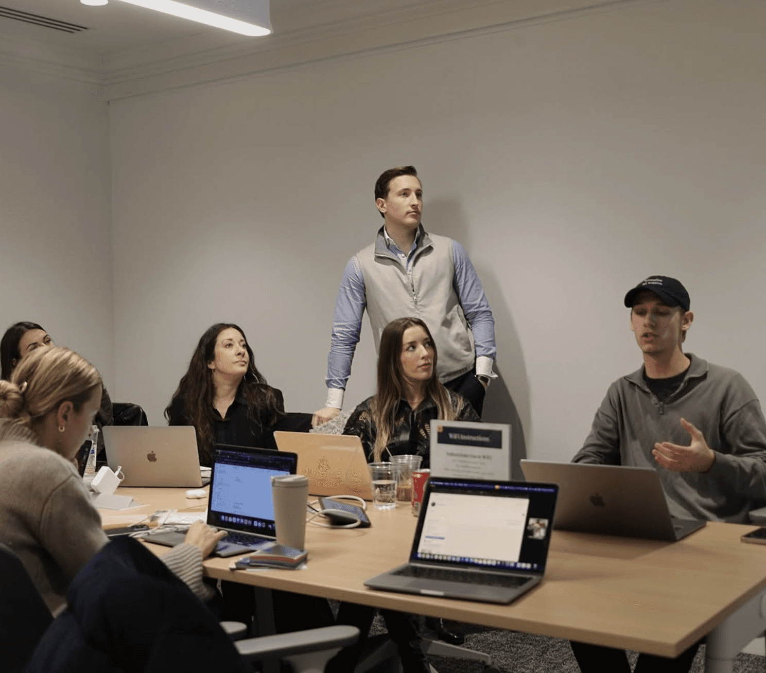 Four diverse professionals collaboratively working on a laptop, with one person pointing at the screen while others observe.