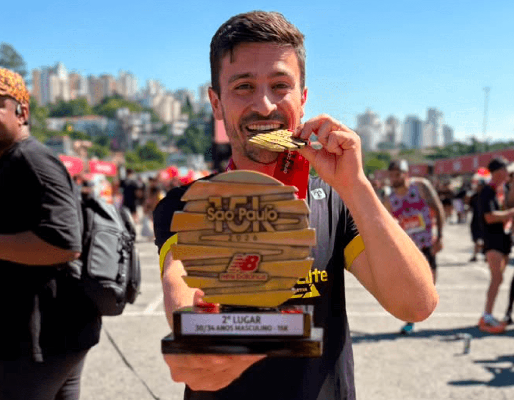Corredor sorrindo com medalha após corrida, representando evolução com método e direção.