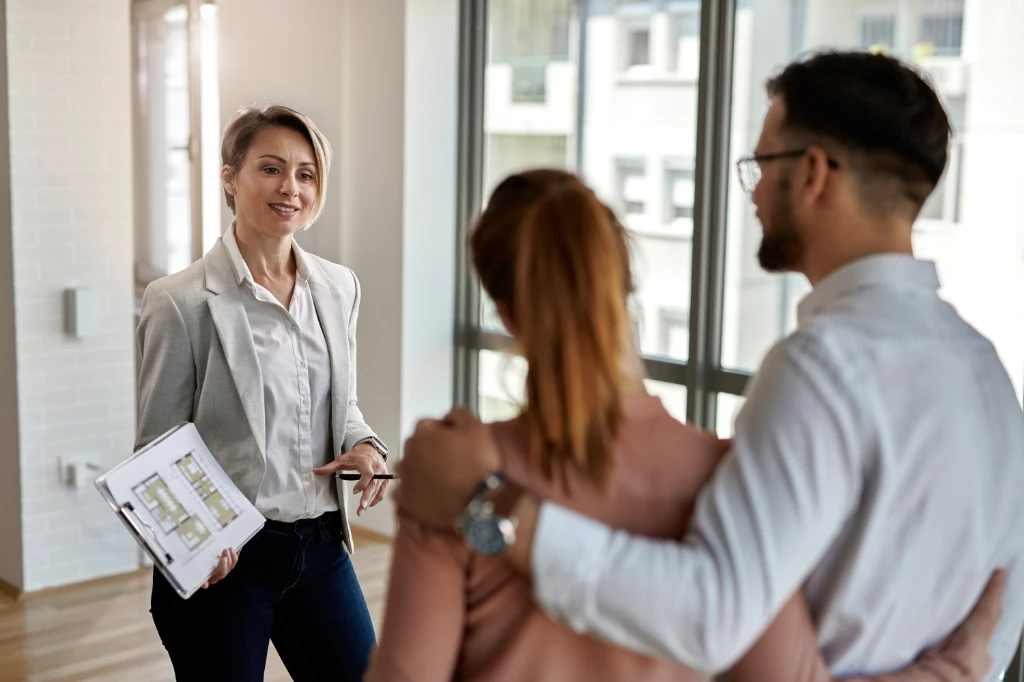 Caucasian real estate agent show clients the floor plan of a home she is showing them