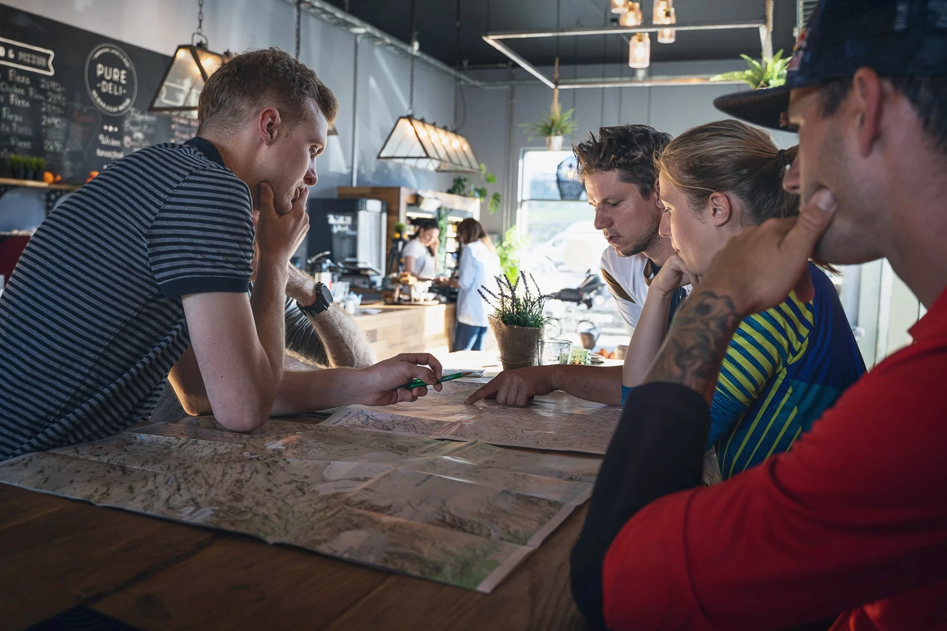 Group leaning over a map in a cafe, planning a route together.