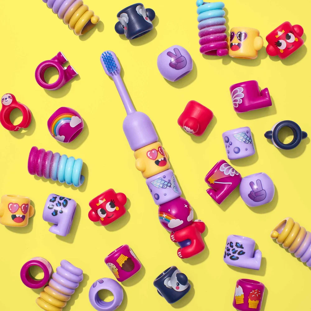 Magenta BABSY Build-A-Brush toothbrush surrounded by colorful interchangeable character pieces