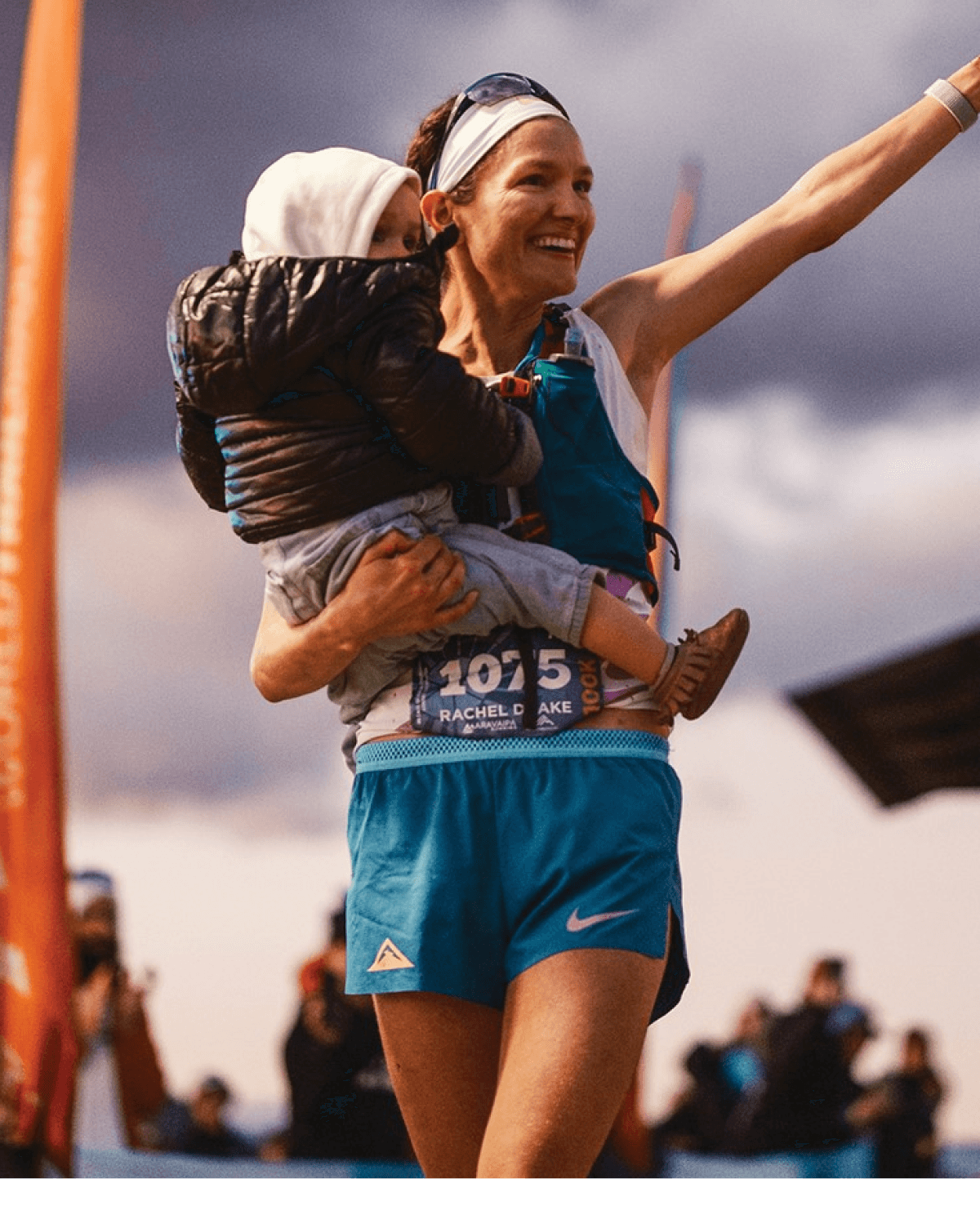 Rachel holding her child and raising her arm in celebration.