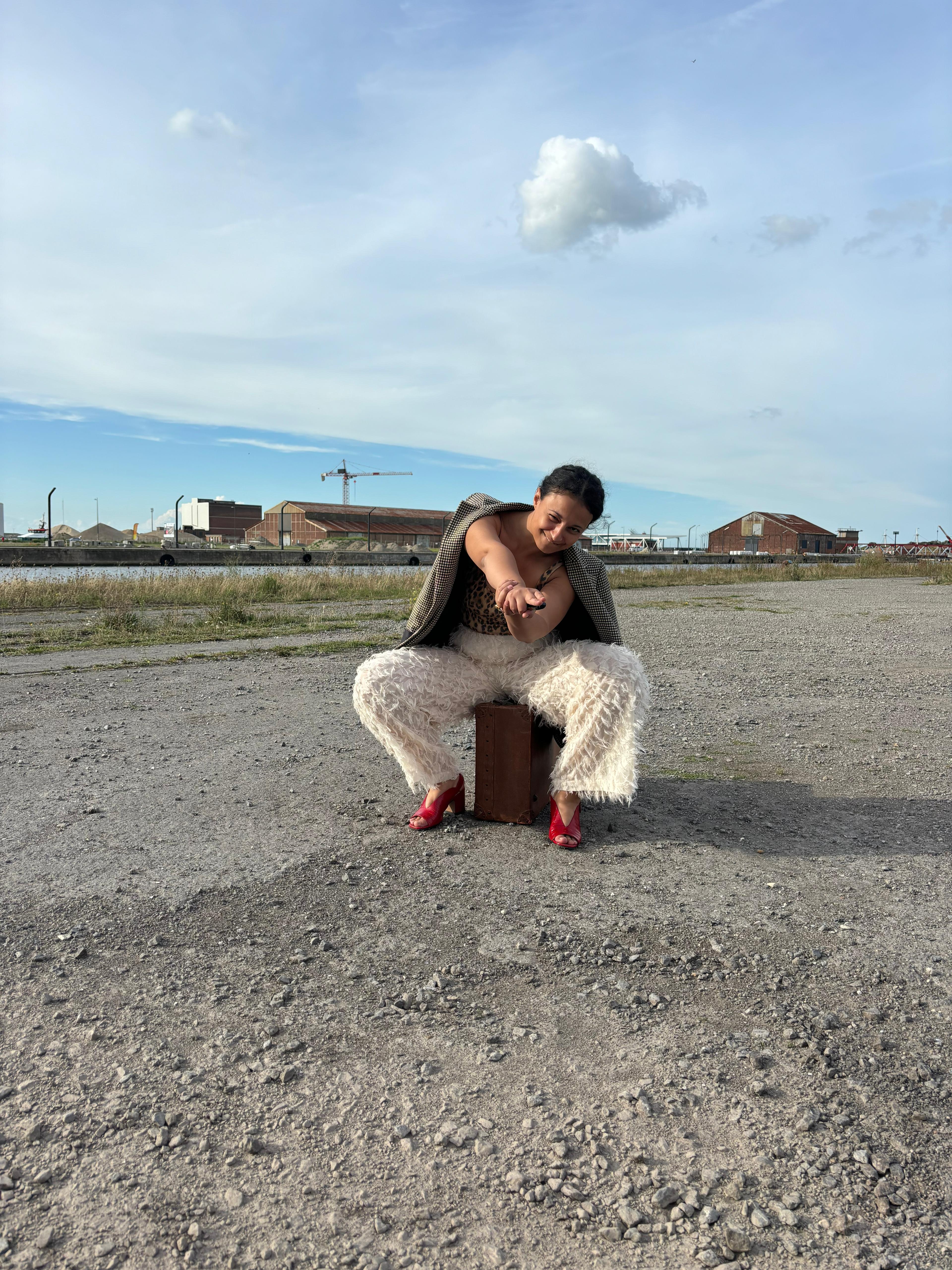 Woman in pink leather jacket crouching outdoors at night
