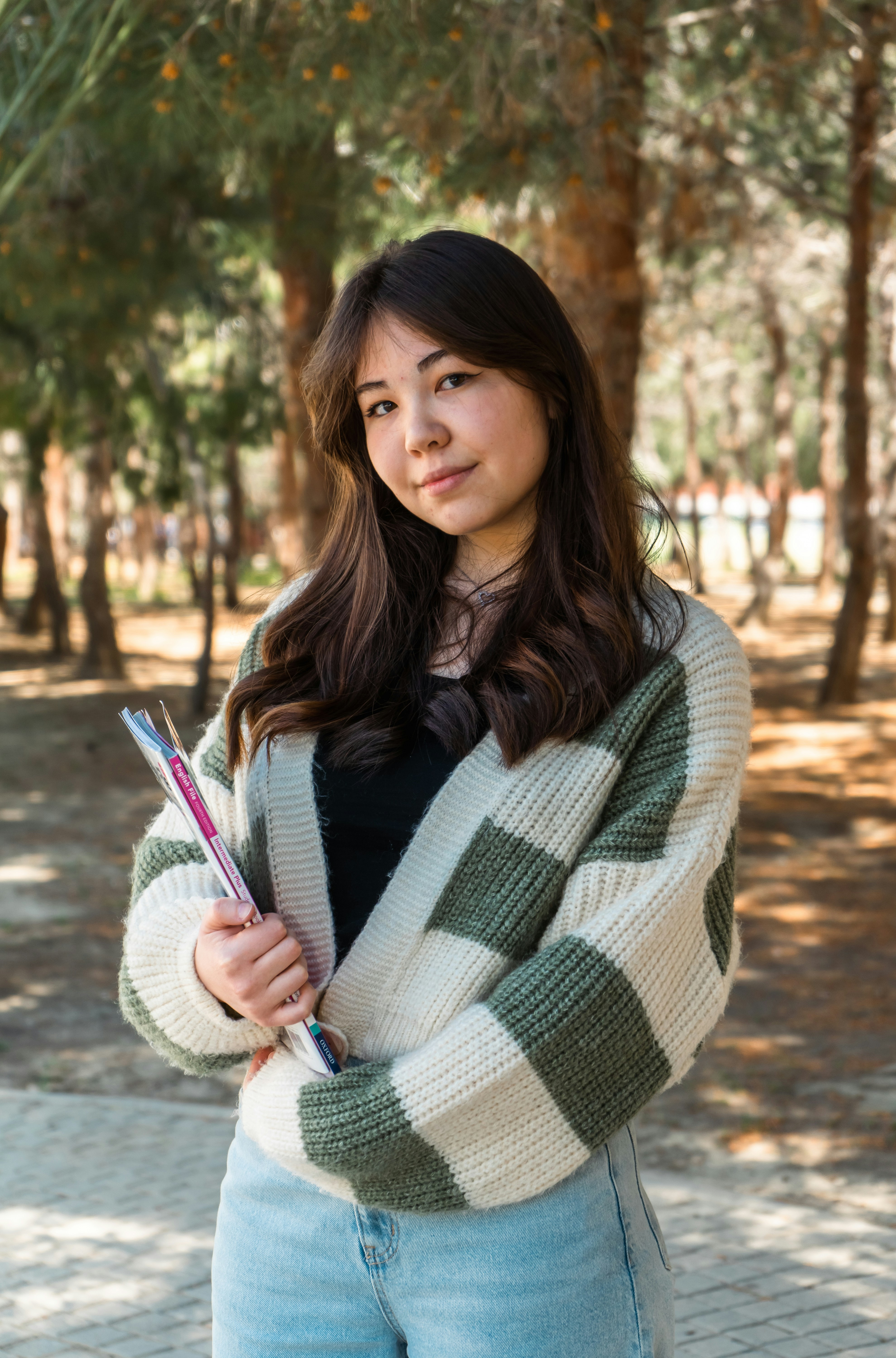 a woman standing in a park with her arms crossed