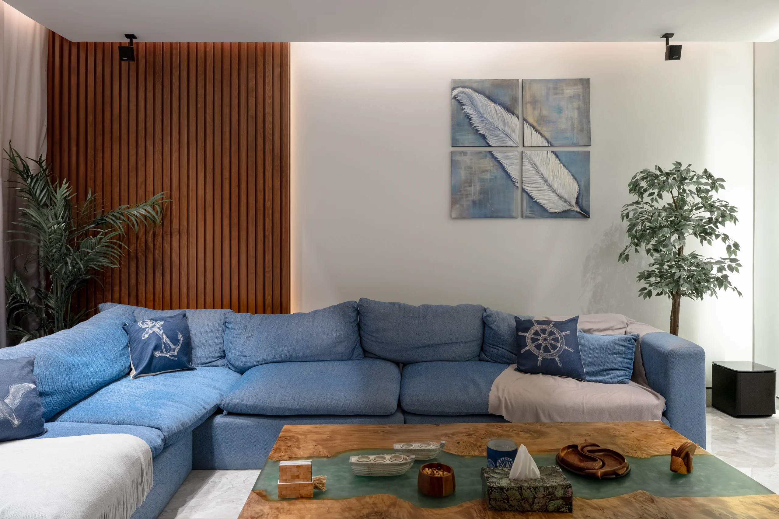 Caesar SODIC Villa lounge with blue sectional sofa, walnut slat wall and indoor planting.