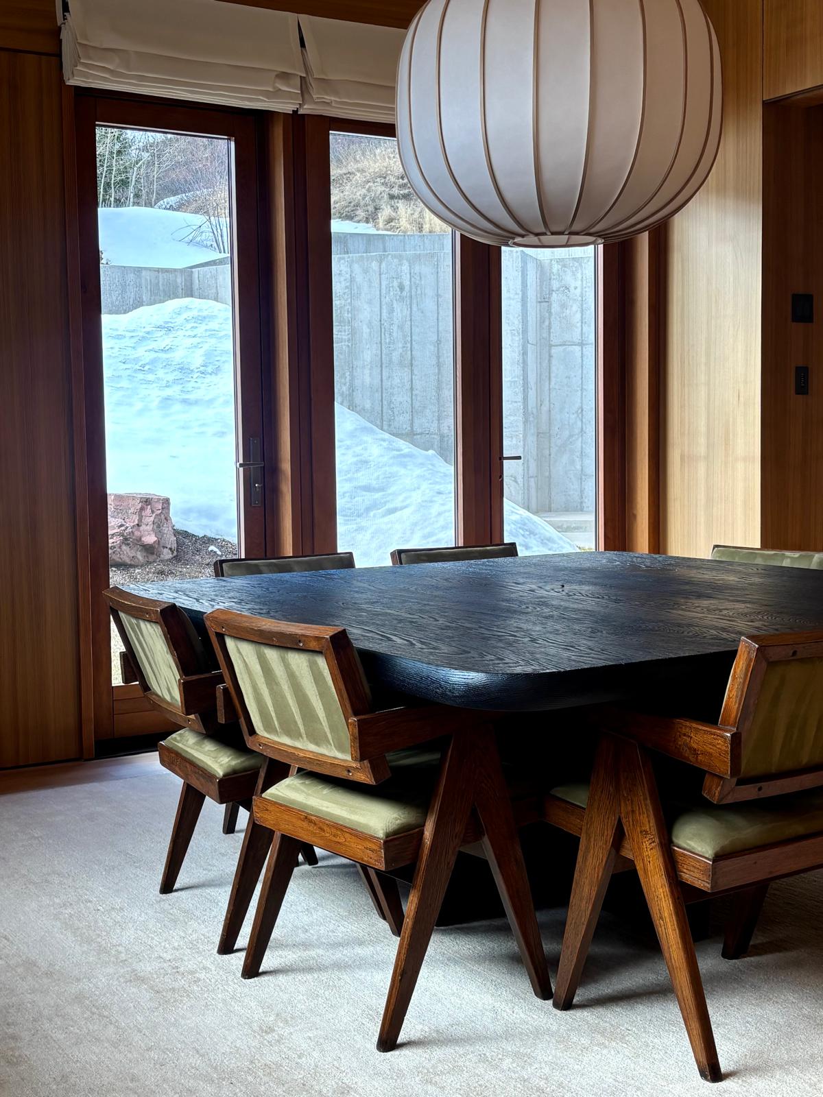 Dining room with a wooden table and mountain views framed by open doors.