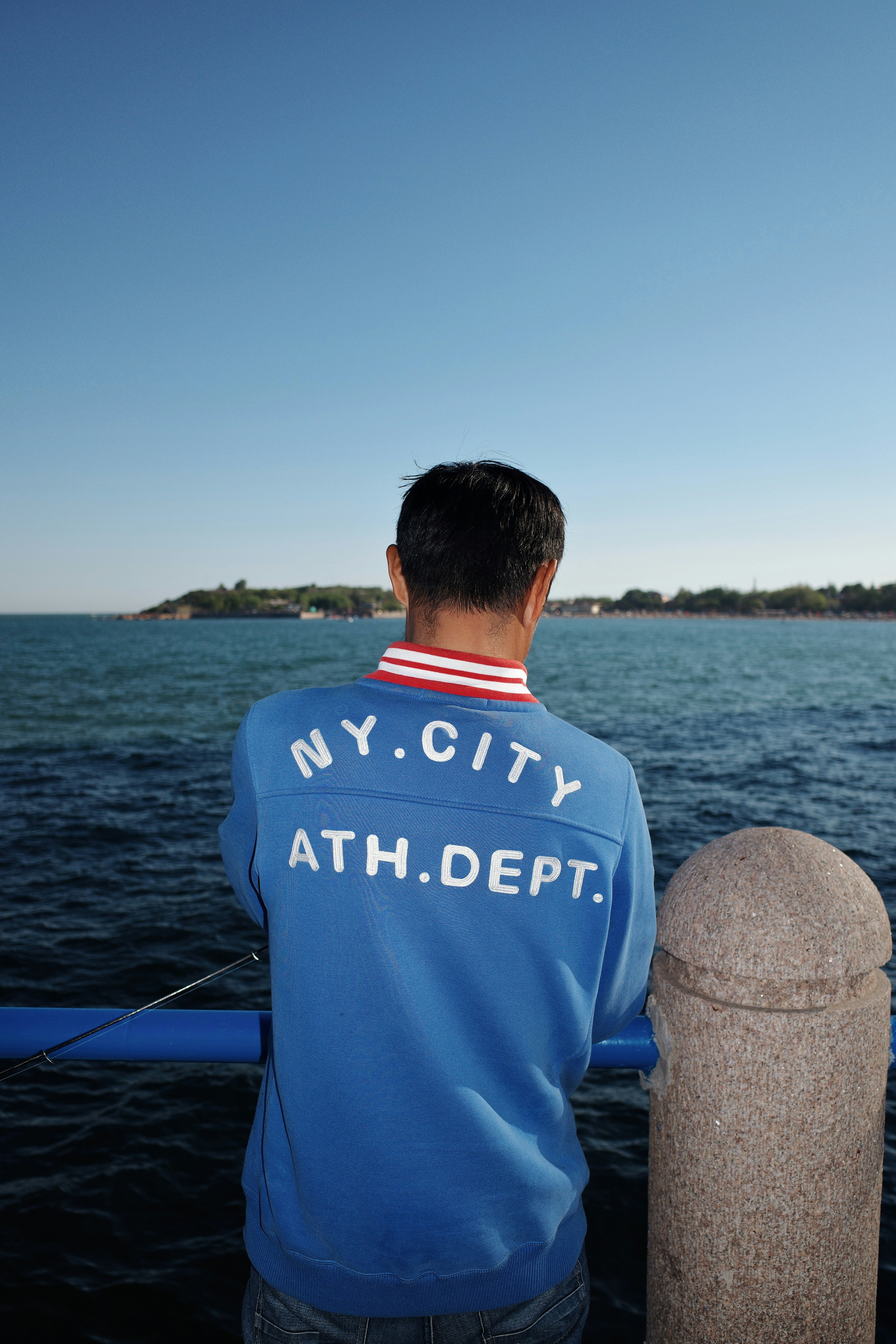 Man in blue sweatshirt looking at the ocean