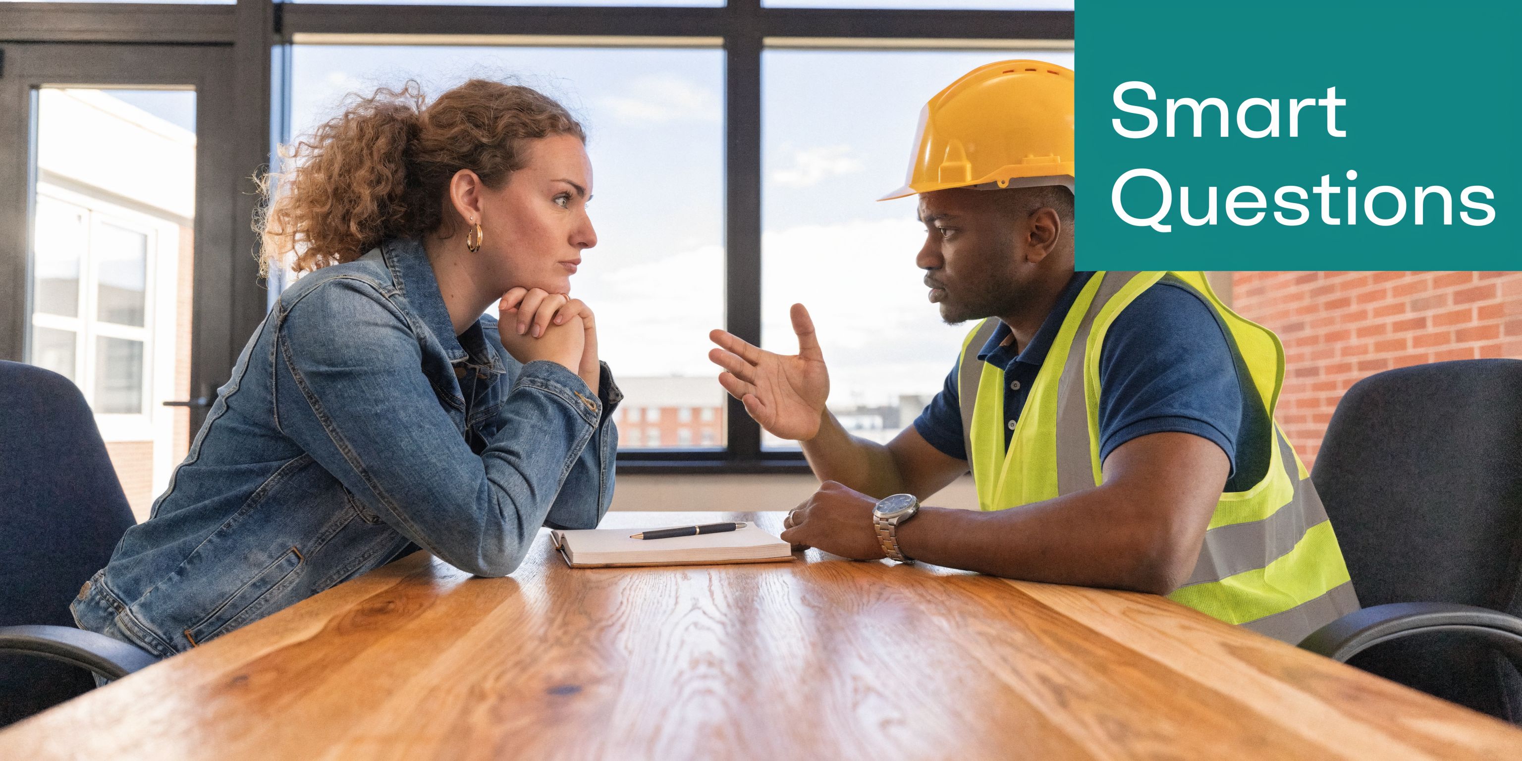 A woman and a contractor in a hard hat having a meeting at a conference table.