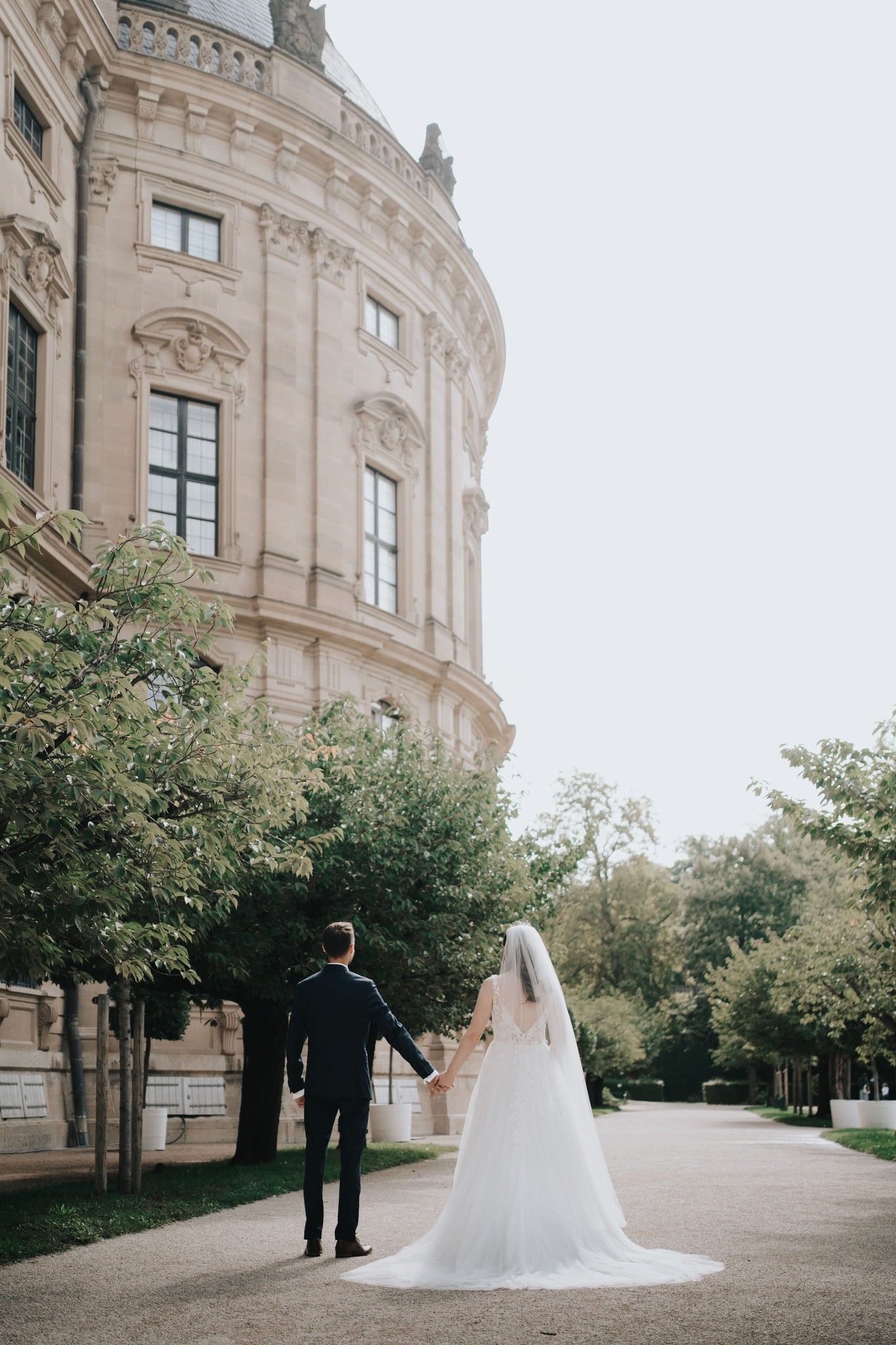 Braut und Bräutigam spazieren Hand in Hand vor historischer Kulisse – zeitlose Hochzeitsreportage in Franken