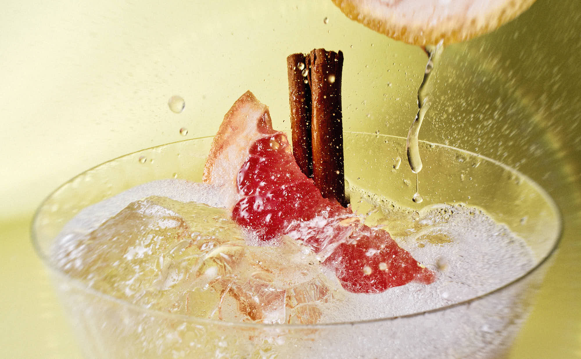 A close-up of a refreshing cocktail in a glass, garnished with fruit and served over ice.