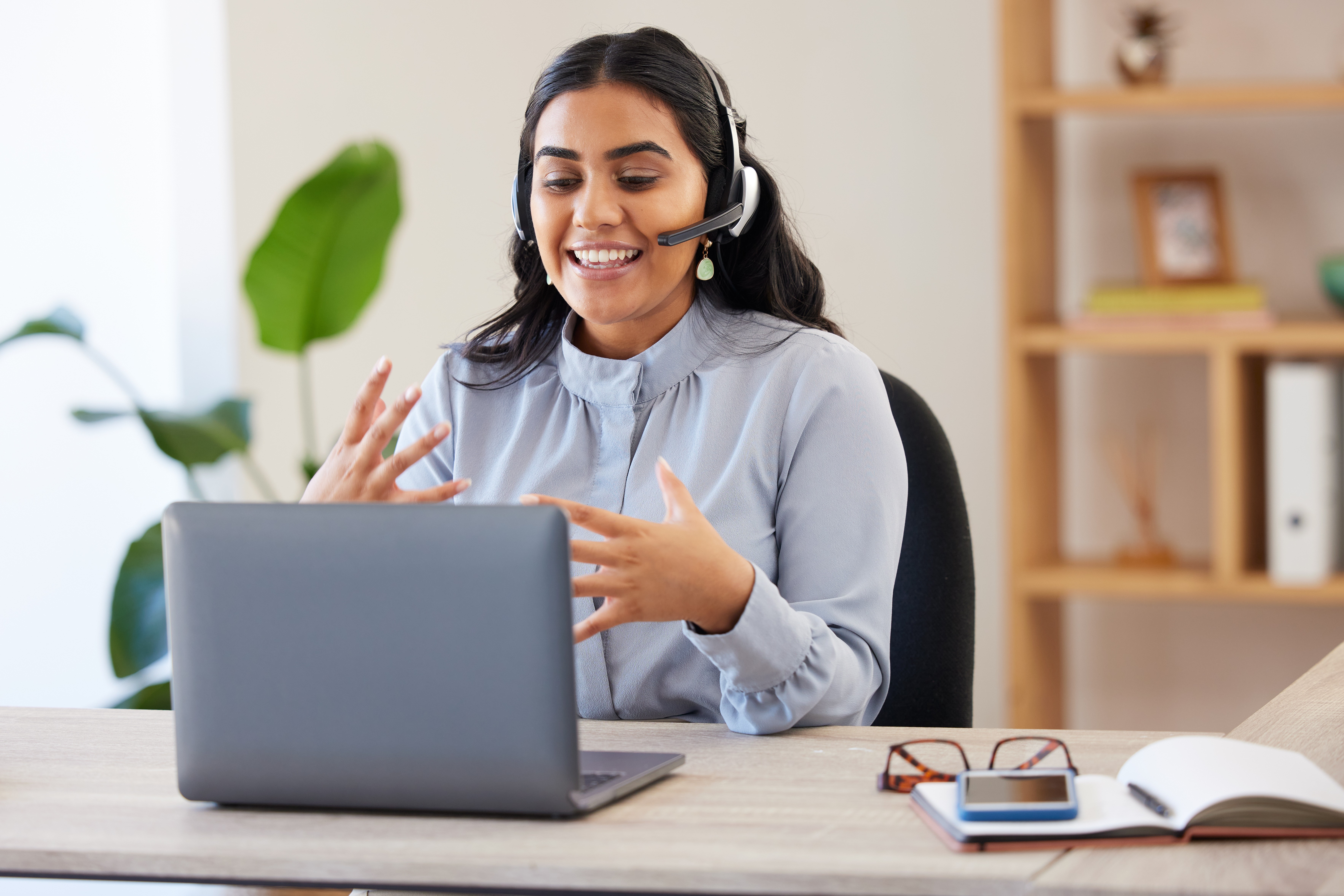 Female remote worker wearing a headset, actively participating in a video meeting, representing accessible and effective offshoring for businesses seeking skilled international talent.