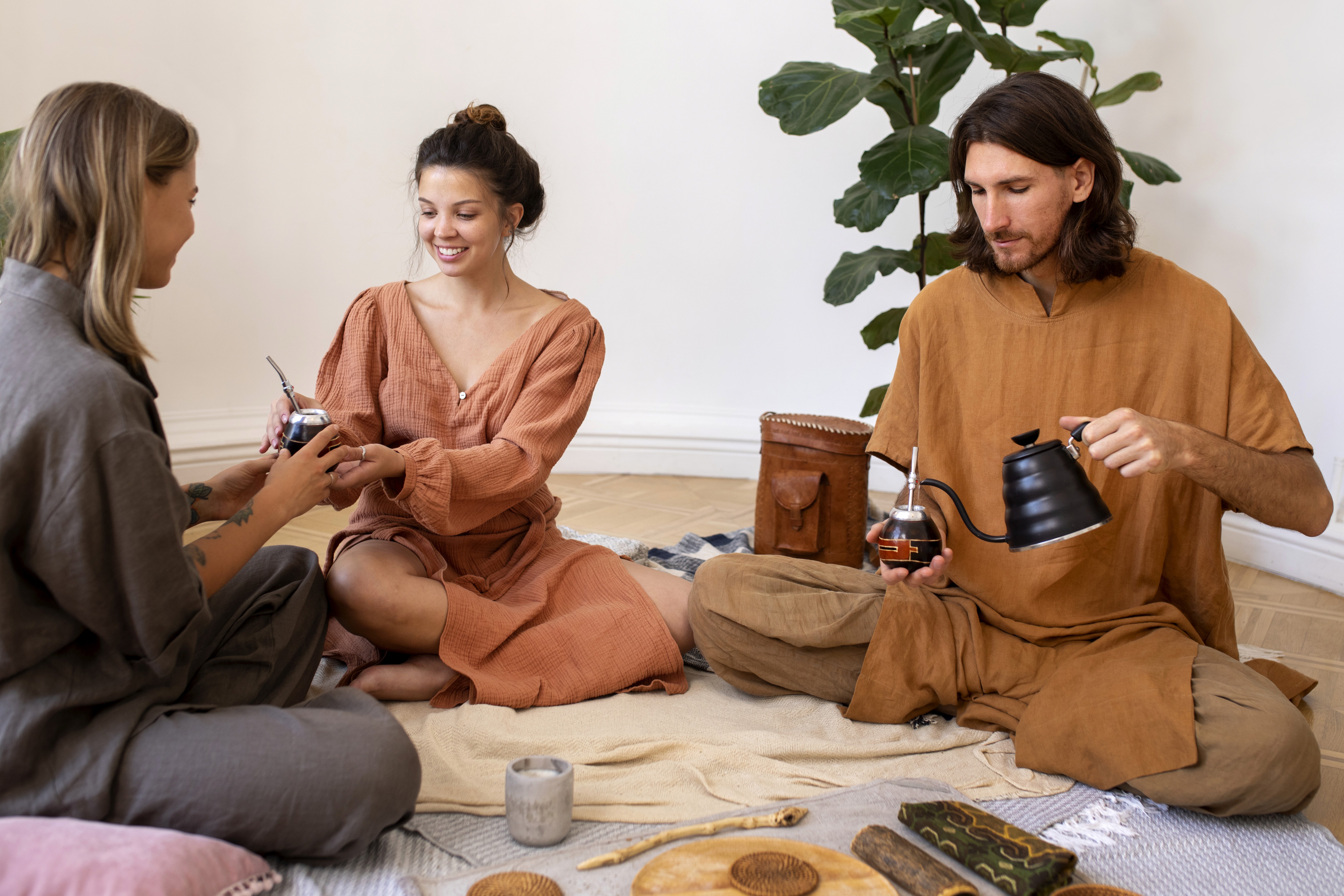 Um grupo pequeno de pessoas sentadas confortavelmente em almofadas de meditação no chão, com os olhos fechados, num ambiente sereno.