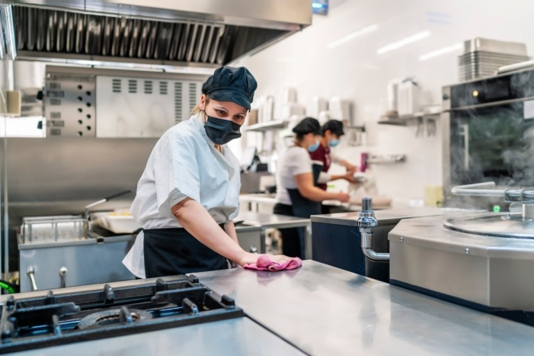Care home kitchen staff wearing masks working in a commercial kitchen, representing agency staffing compliance and workforce management