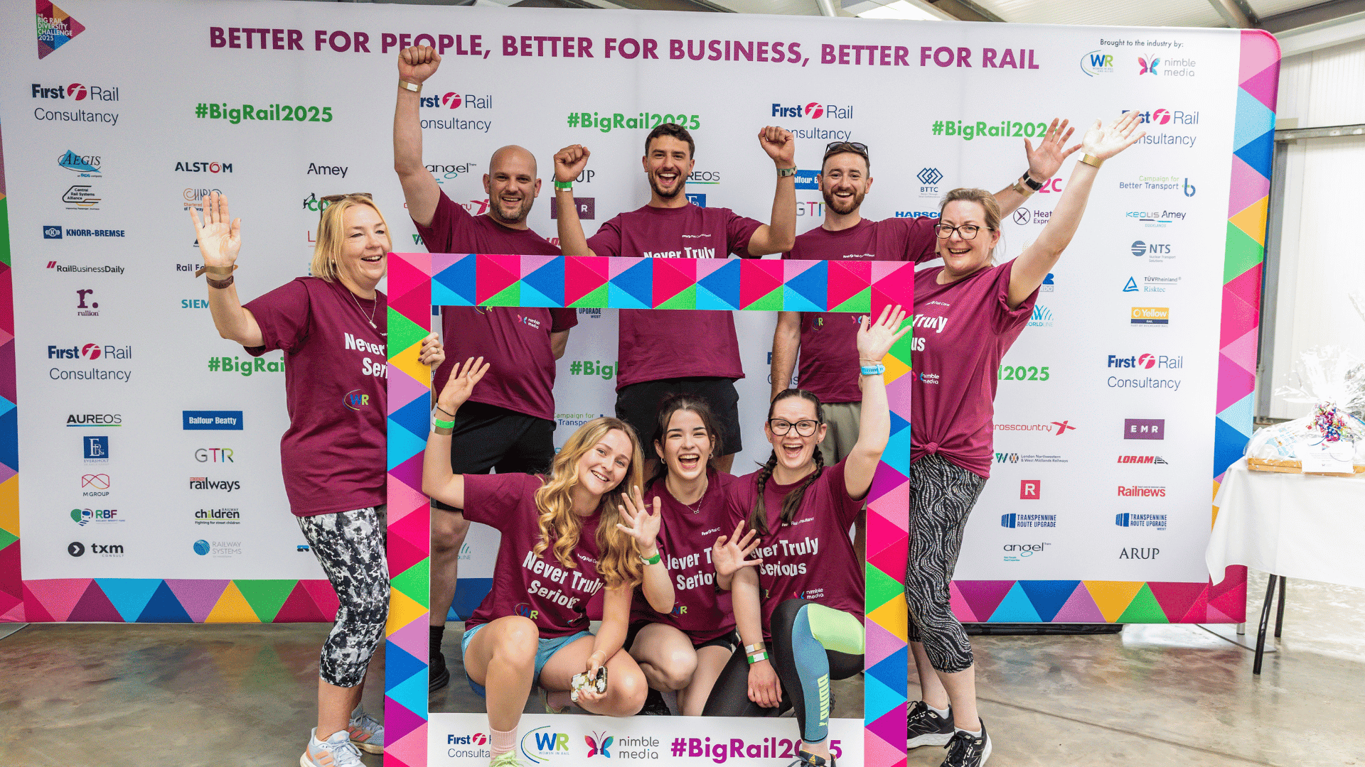 Outdoor team-building event with participants wearing matching blue shirts, taking part in inflatable obstacle courses and games, smiling and cheering, with the words 'ENTER A TEAM' in large bold white and green text across the image.