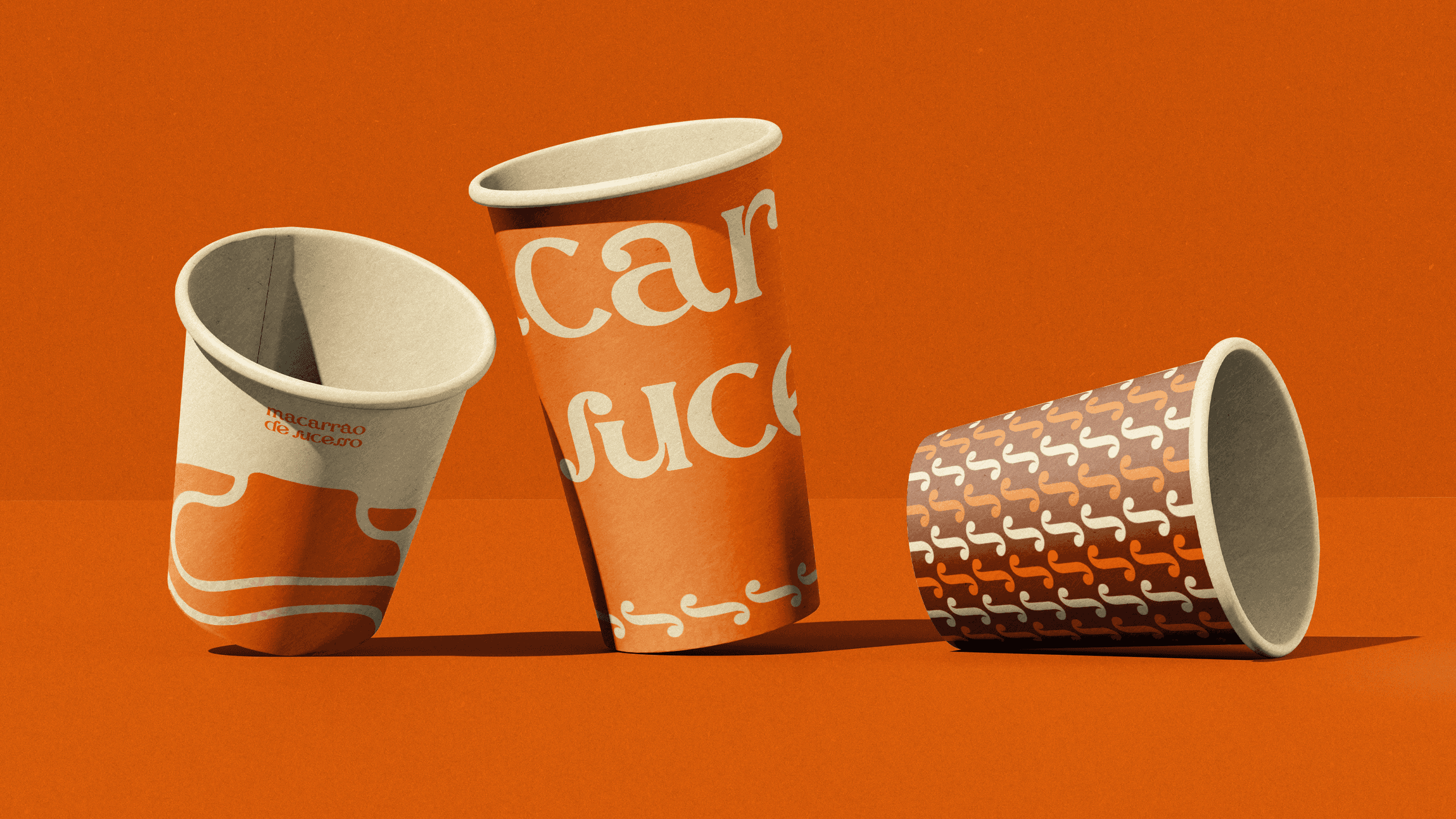 três copos sobre um fundo laranja, em cada um dos elementos, grafismos e ativos visuais da marca macarrão de sucesso são exibidos.