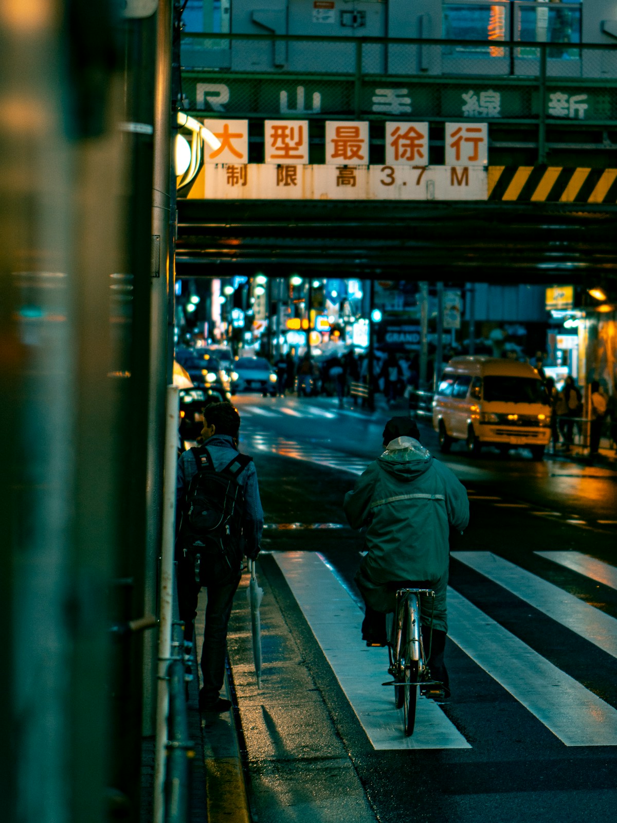 A cyclist crossing a neon-lit city street at night