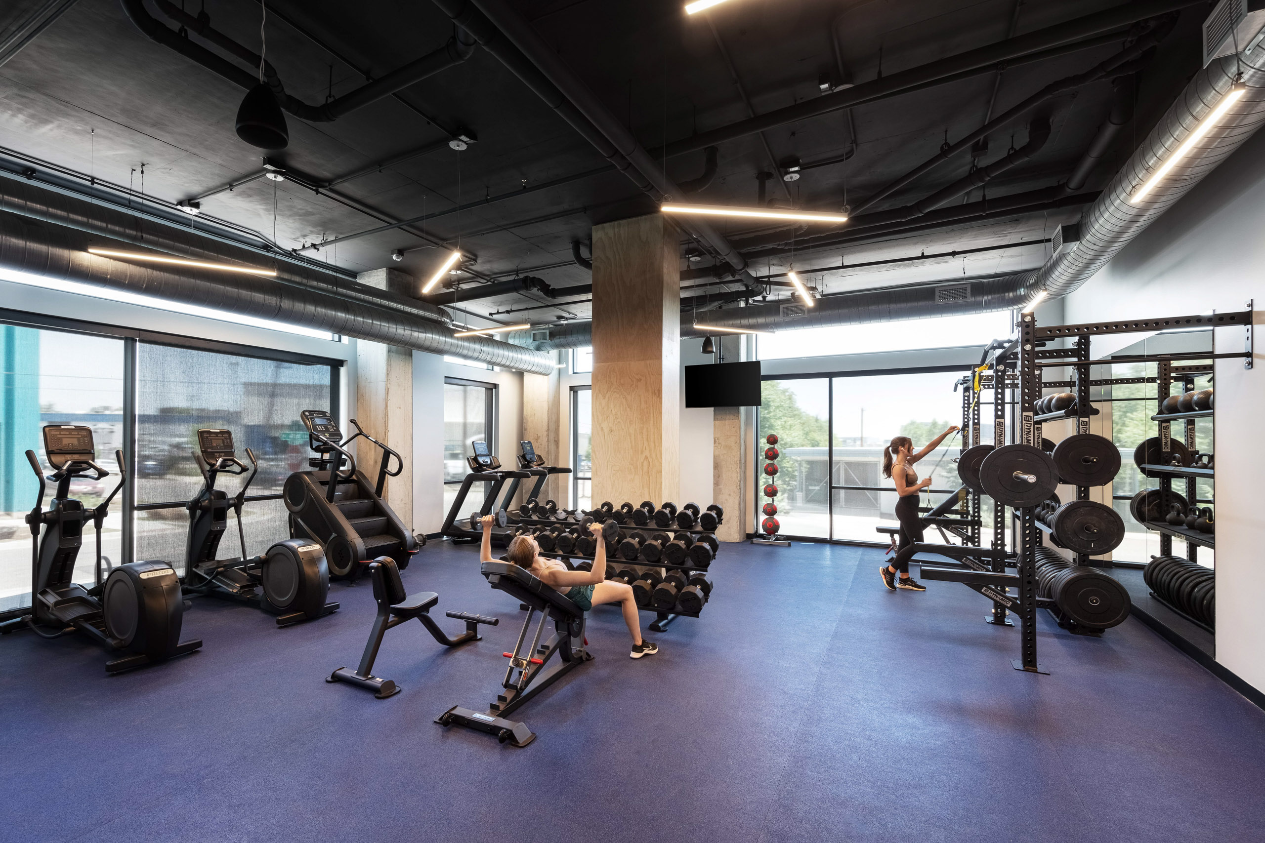 Gym interior with workout equipment and people training.
