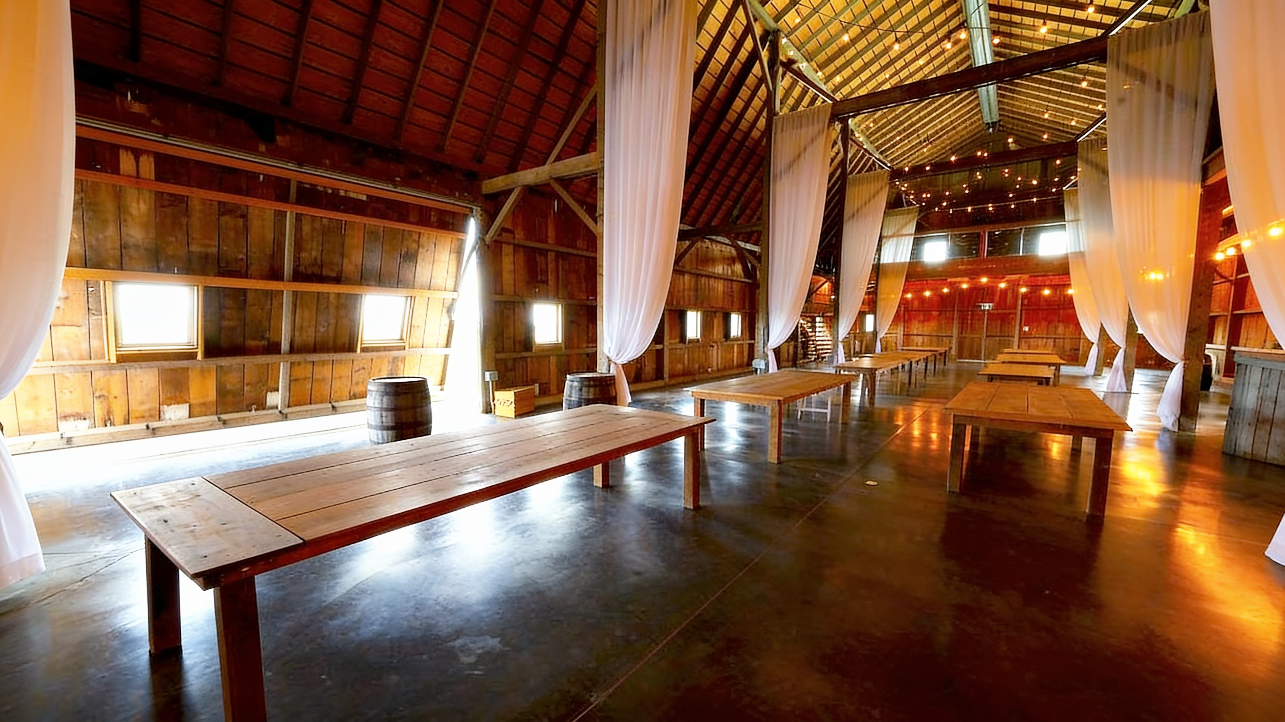 Interior of a restored barn wedding venue with draped lighting