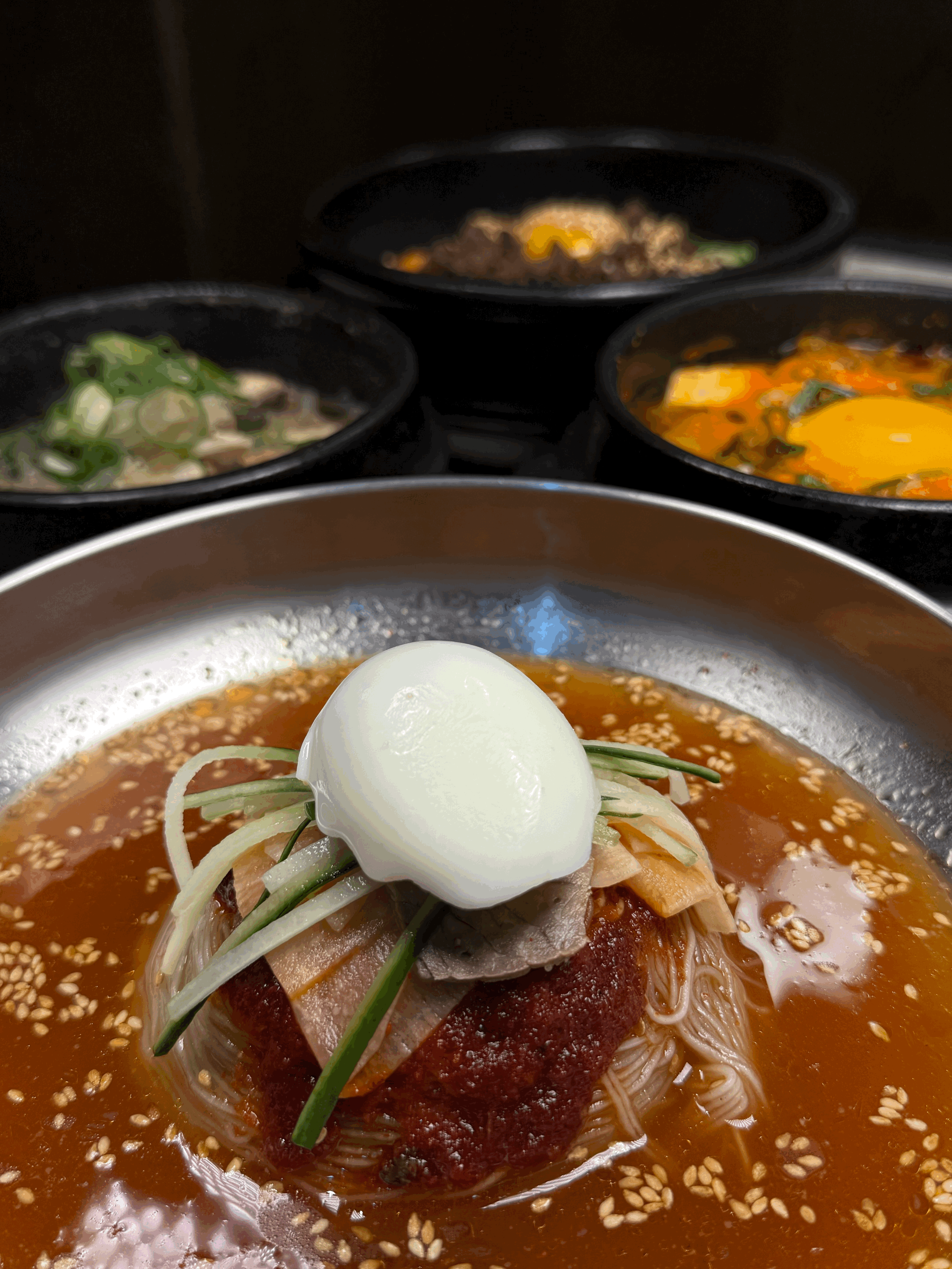 A cluttered dining table with plates, glasses, and food remnants, illuminated by soft, warm lighting.