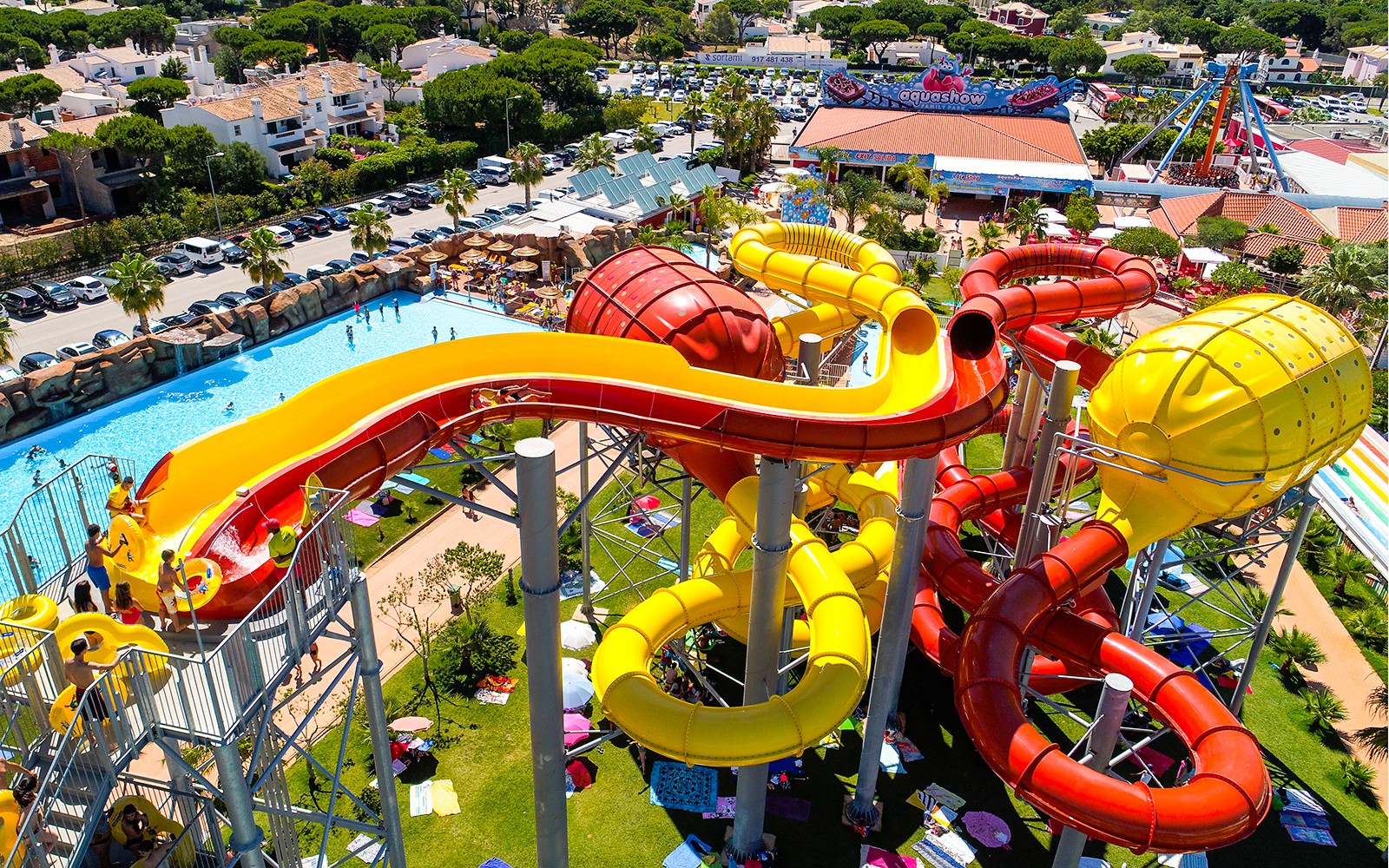 Tobogãs aquáticos coloridos no Aquashow Park, Portugal, com visitantes aproveitando as atrações.
