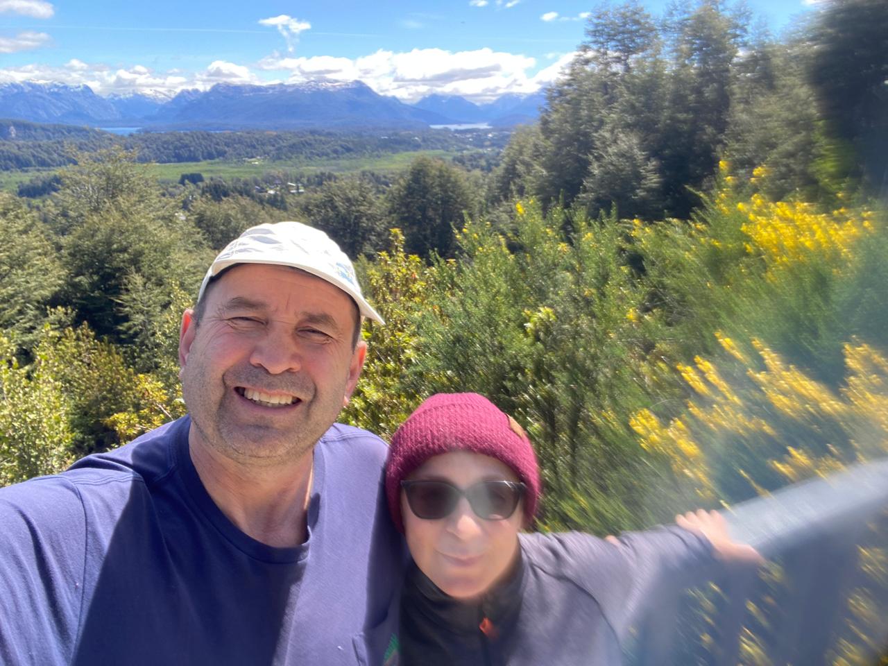 Mujer sentada sobre un tronco frente a una cascada doble en un bosque frondoso de Argentina.