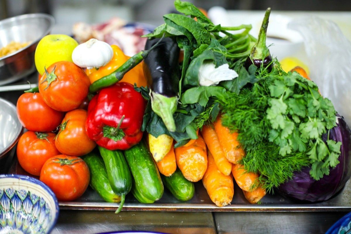 A tray of colorful fresh vegetables including tomatoes, peppers, carrots, and leafy greens that support gut health