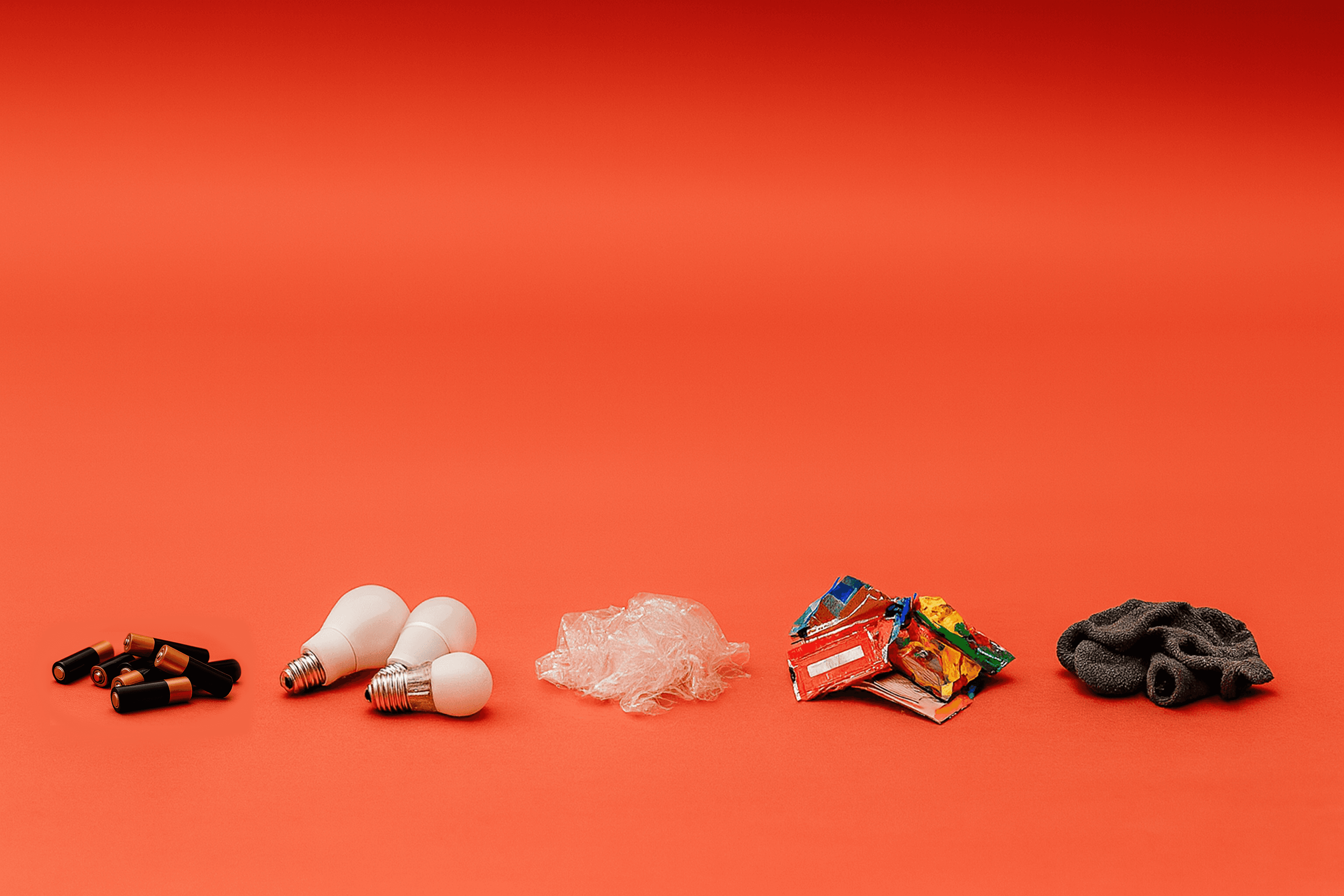 Hard to recycle items in small piles on an orange background
