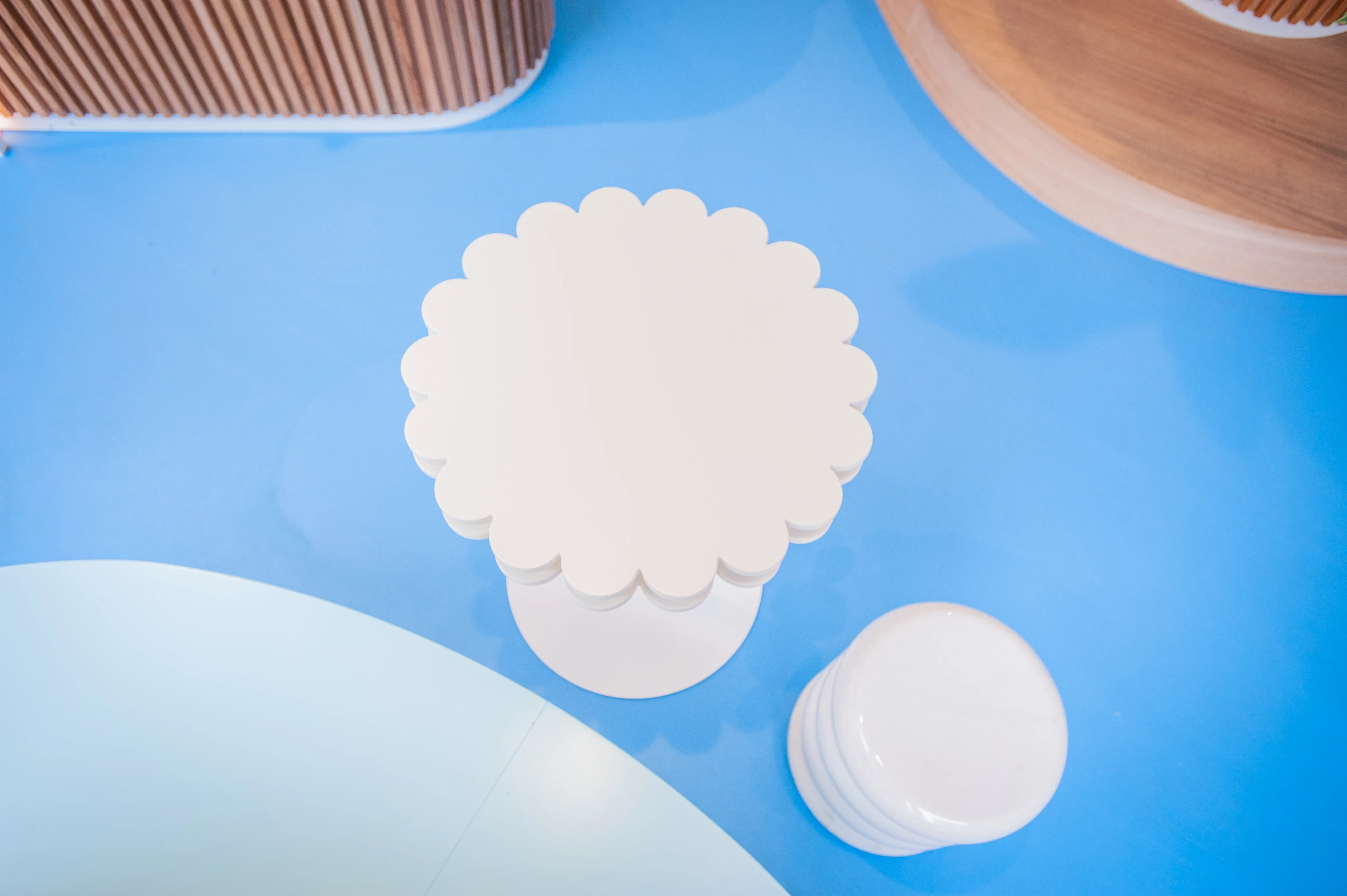 Top view of a white flower-shaped table and ribbed stool on the bright blue floor of the Alpro pop-up.