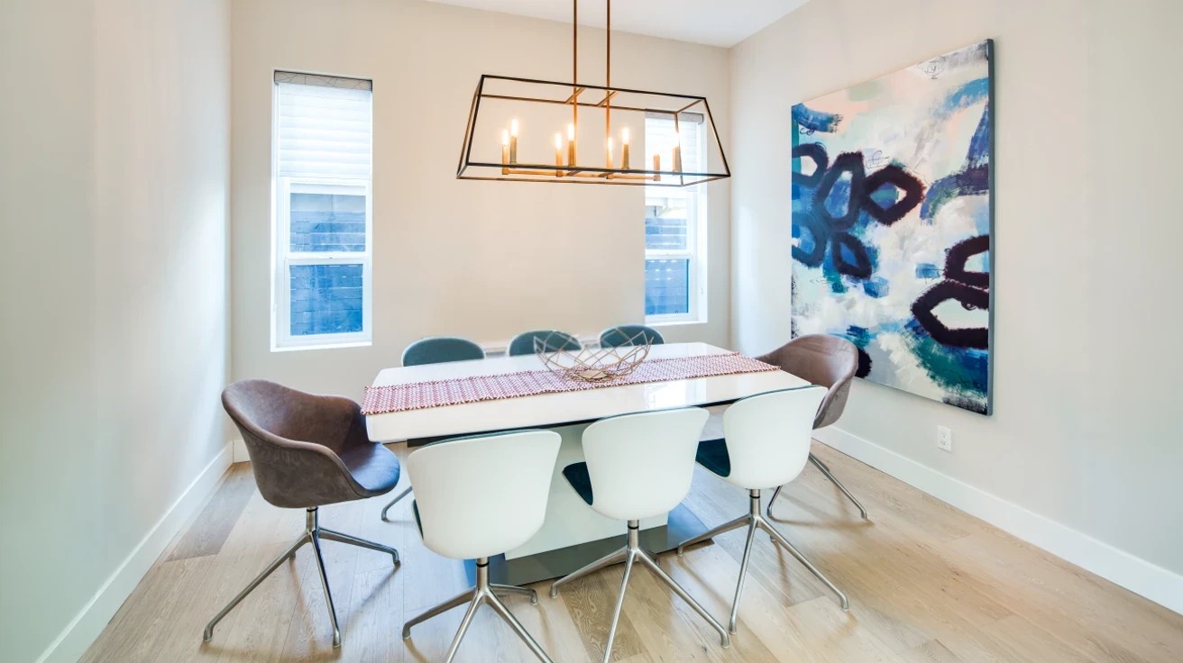  Contemporary dining room with designer linear chandelier, modern dining table and chairs, light hardwood flooring, and abundant natural light