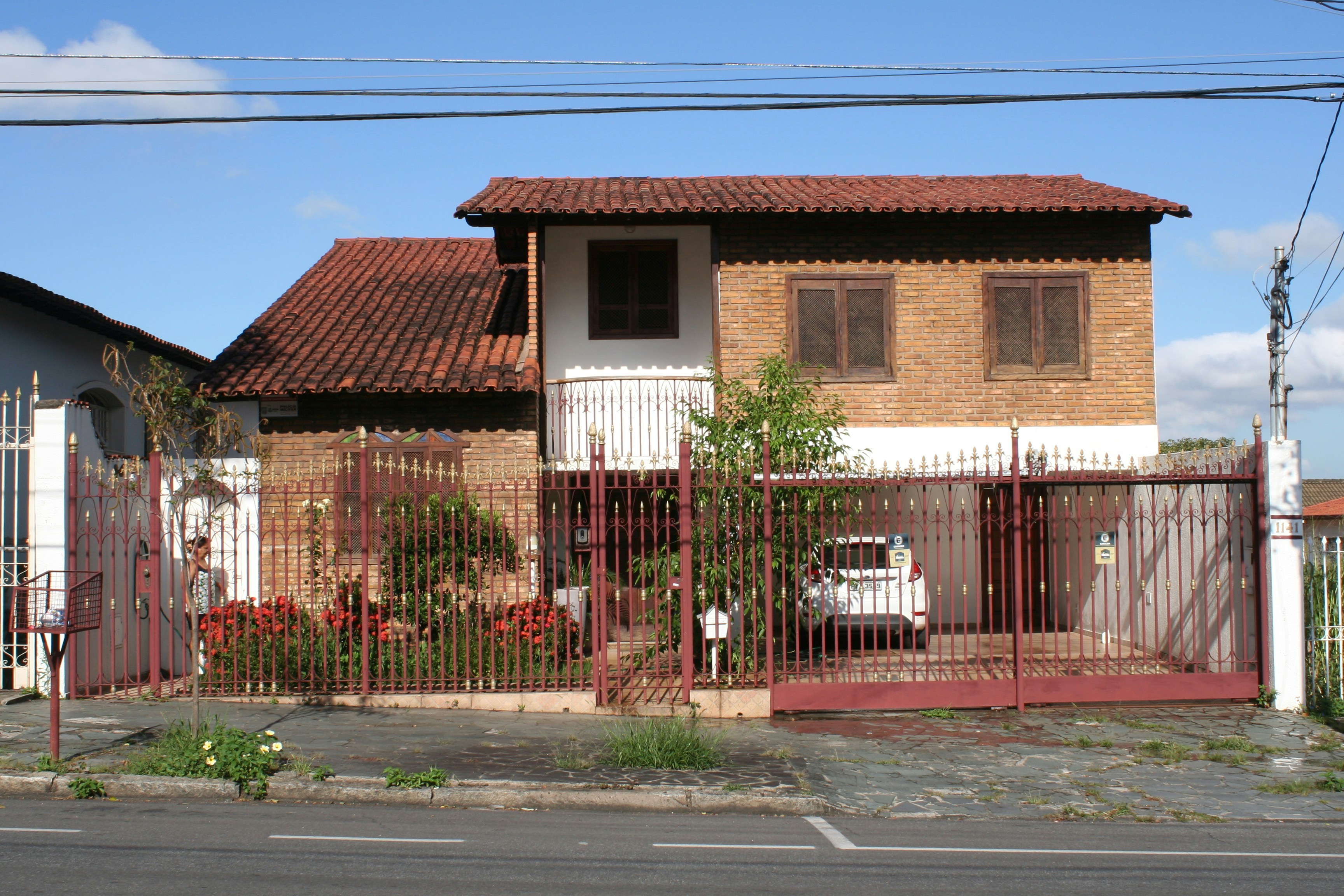 a house behind a fence with a car parked in front of it