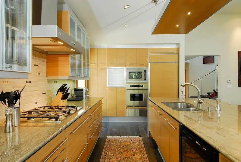 Modern kitchen with warm wood cabinets, stainless steel appliances, and sleek countertops. Irvine Transitional Modern Project. Photo by Chris Darnall.