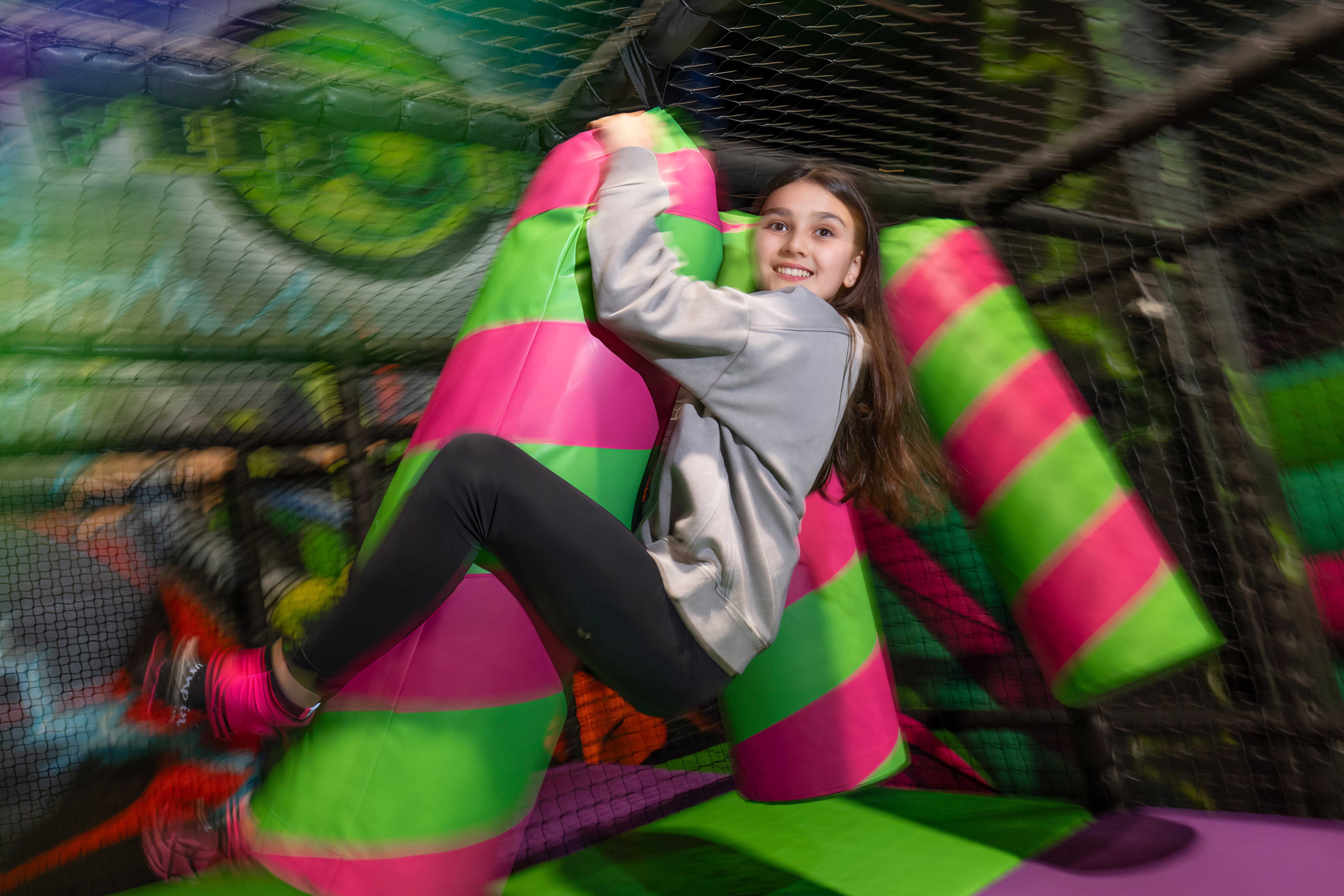 young girl hanging onto bright coloured play area at Flip Out adventure park