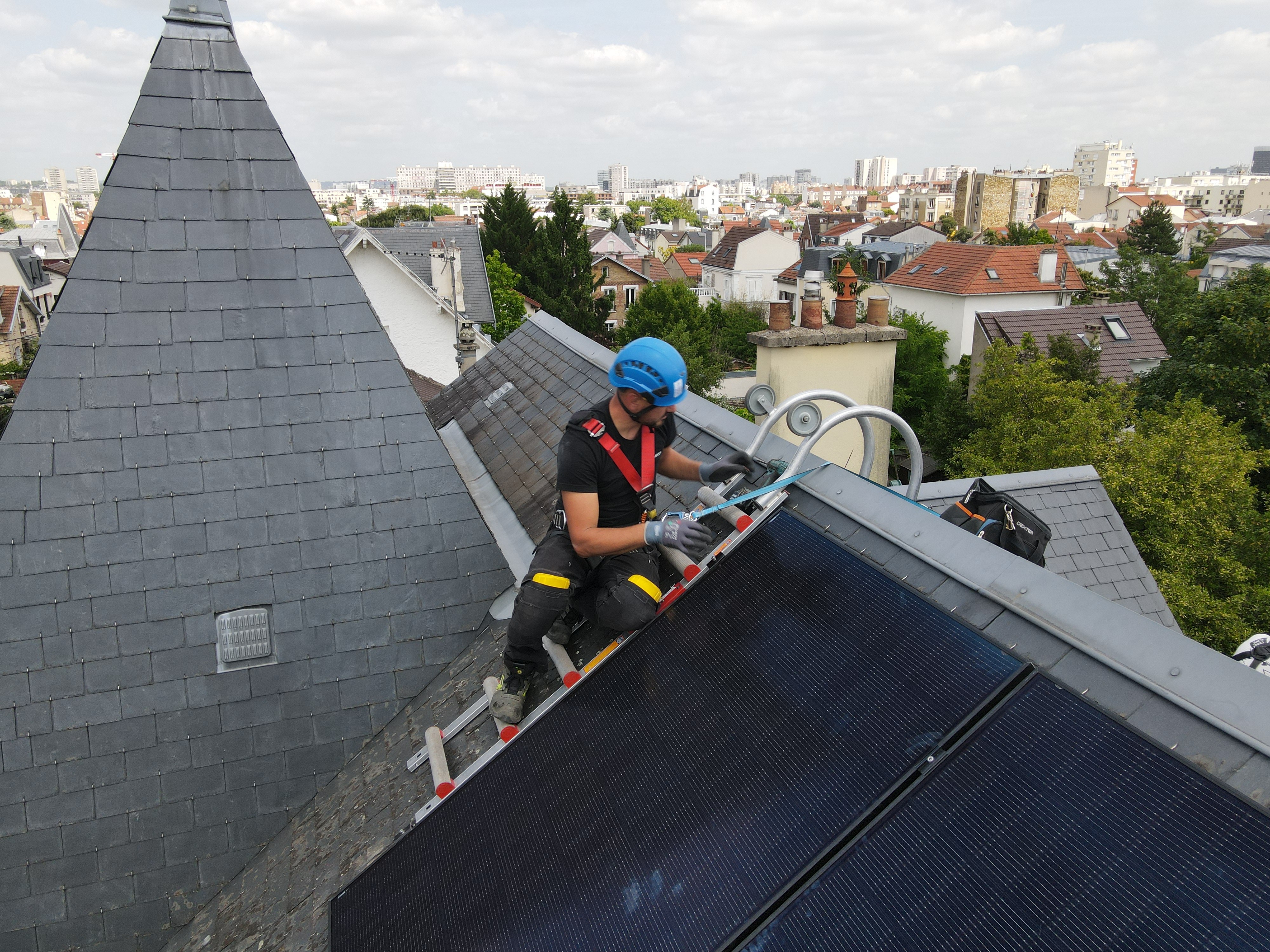 Photo d’un employé Solarock qui installe des panneaux solaires sur le toit en tuile d’une maison.